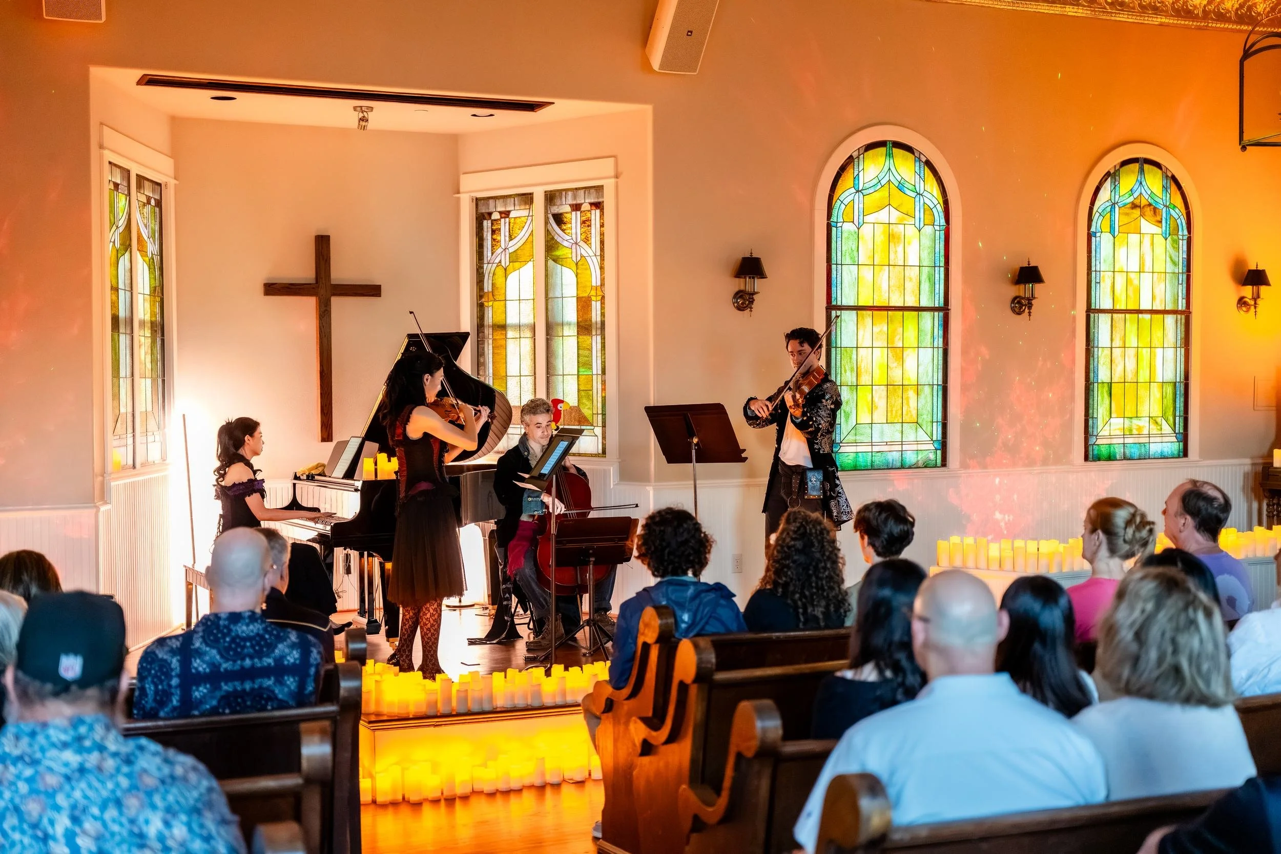 Audience in the pews watching the musicians beneath the cross and stained glass