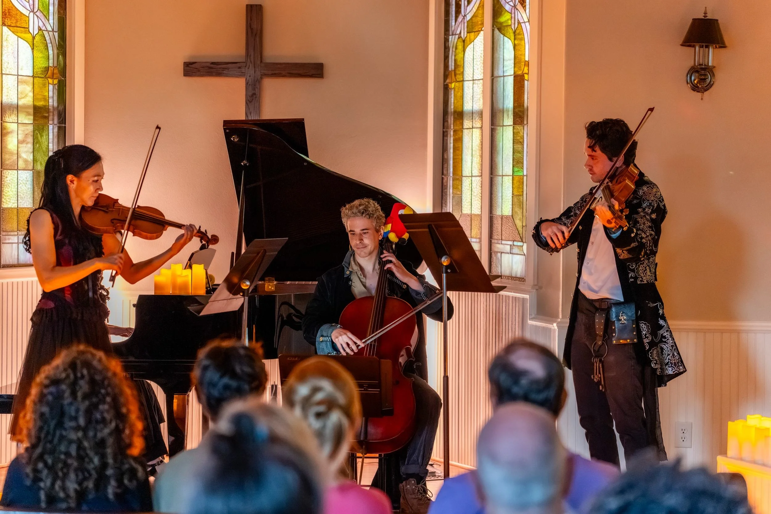 Violinist, cellist, and string player performing for the front rows
