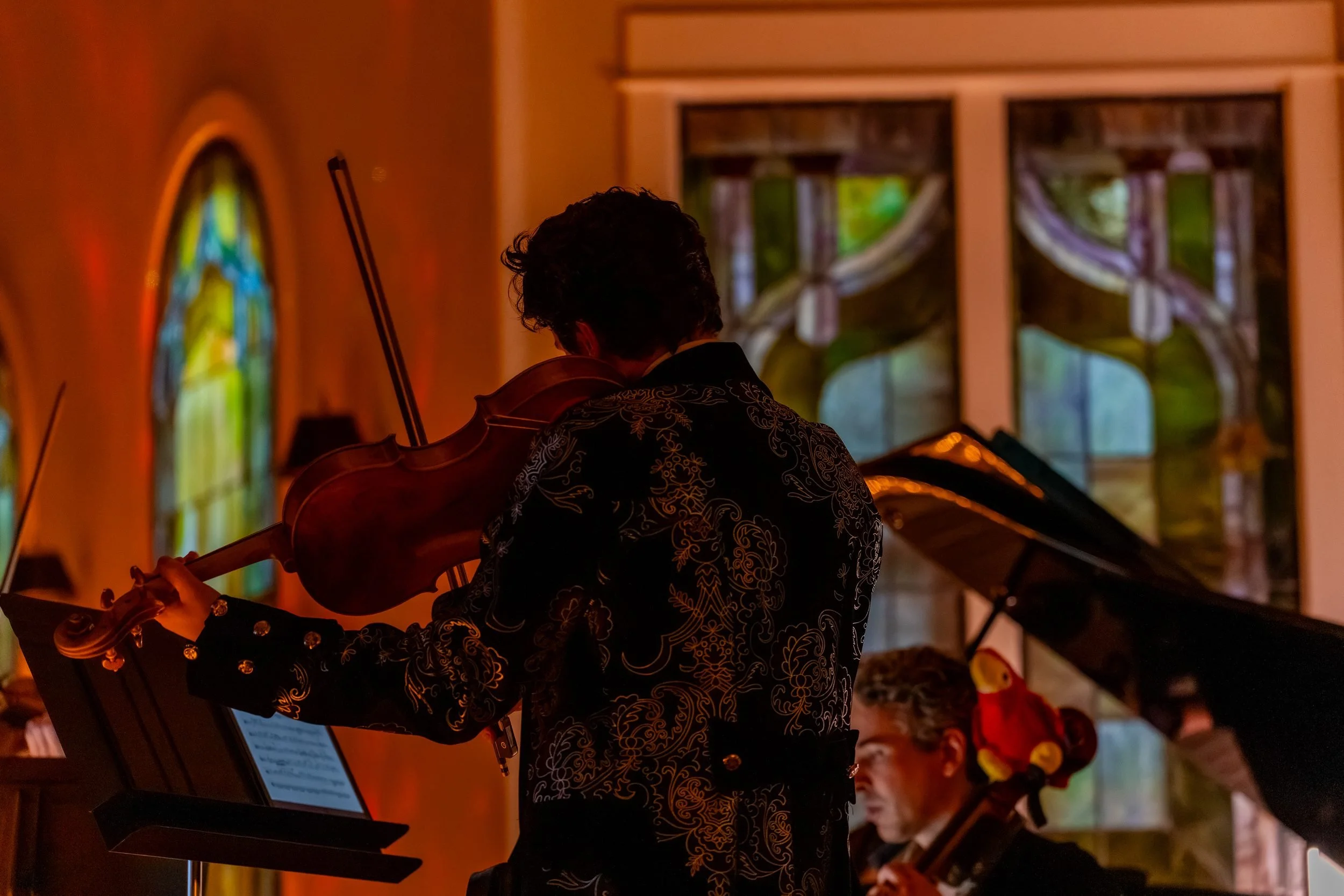 String player with bow raised, seen from the side of the stage
