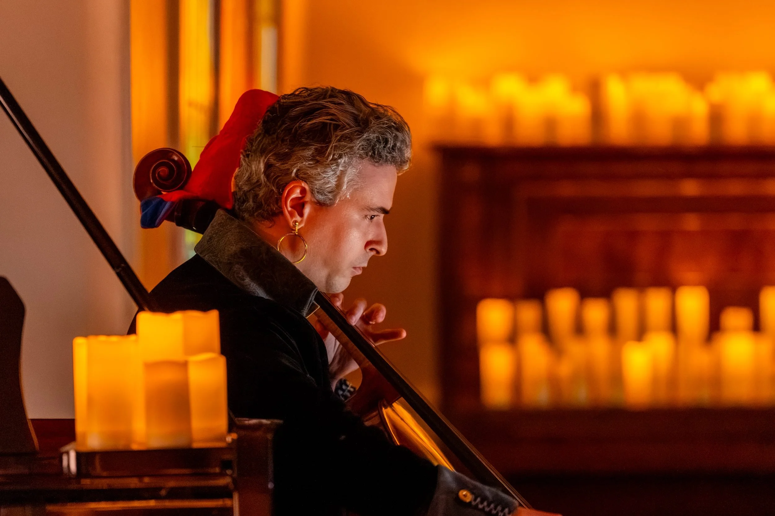 Cellist in profile in front of a wall of candles