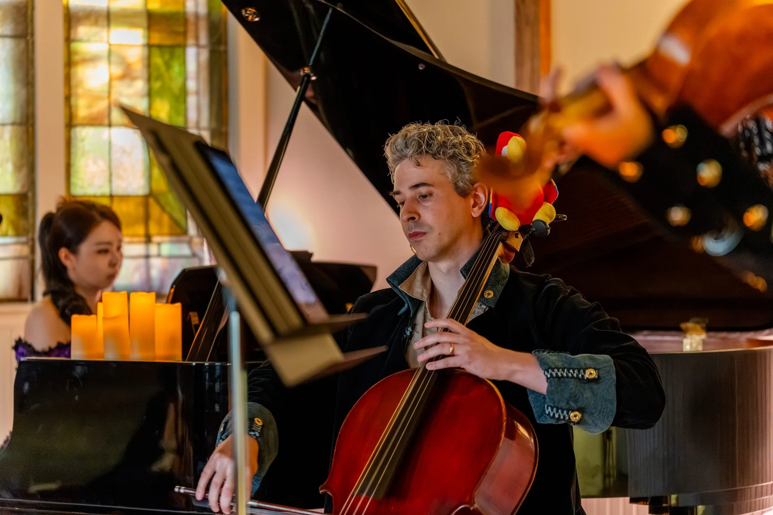 Cellist with the toy parrot on his cello, pianist and candles behind him