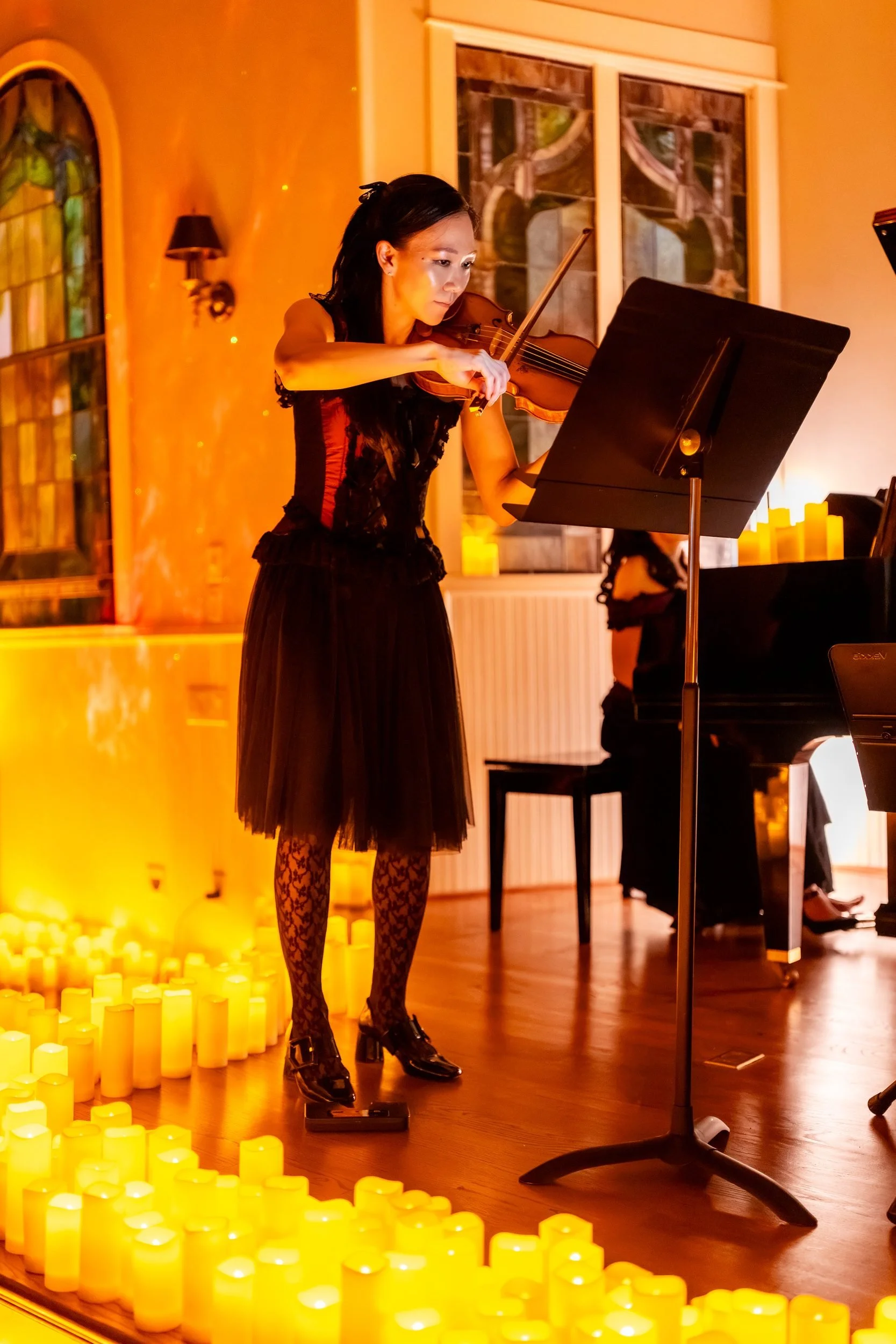 Violinist standing among floor candles