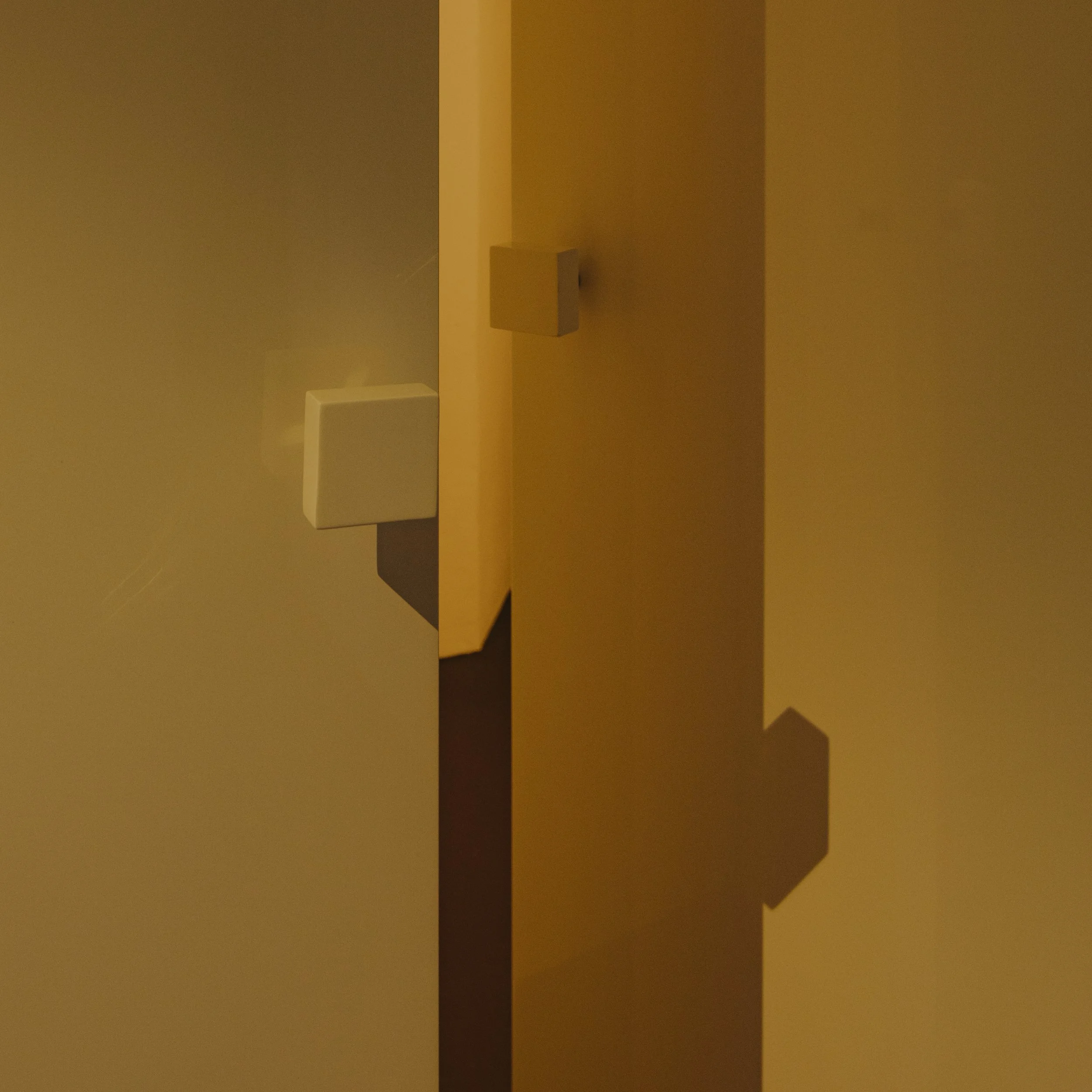 Interior hallway with doors and rectangular wall-mounted fixtures, painted in neutral tones.