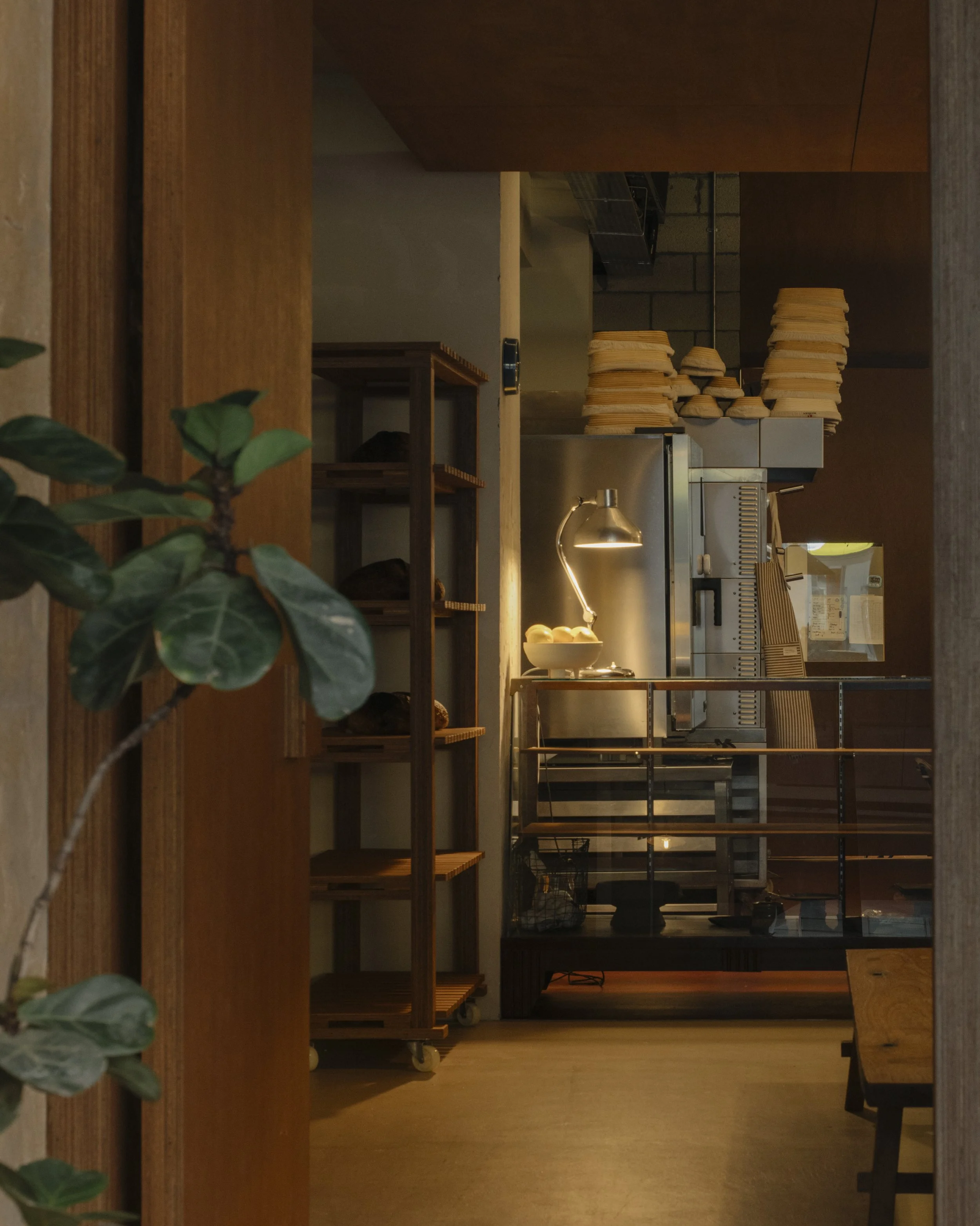 Interior of a restaurant kitchen with stacks of plates, a lamp, and a stainless steel refrigerator.