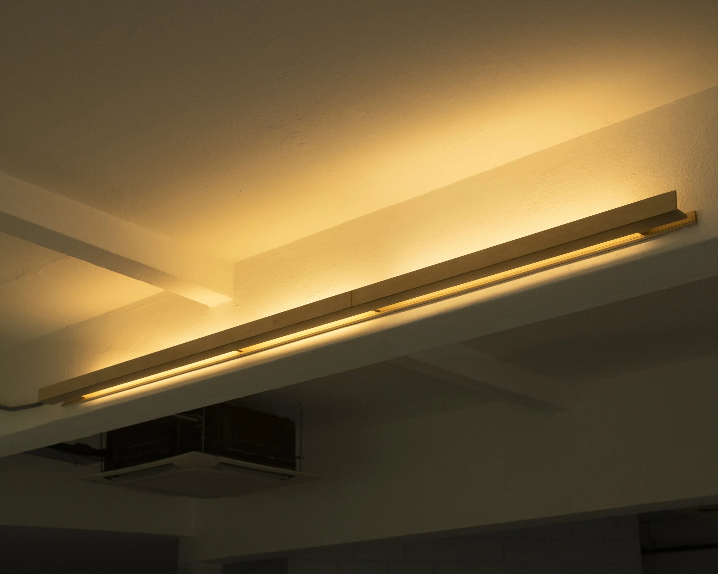 Ceiling with modern, minimalist recessed lighting that emits a warm glow.
