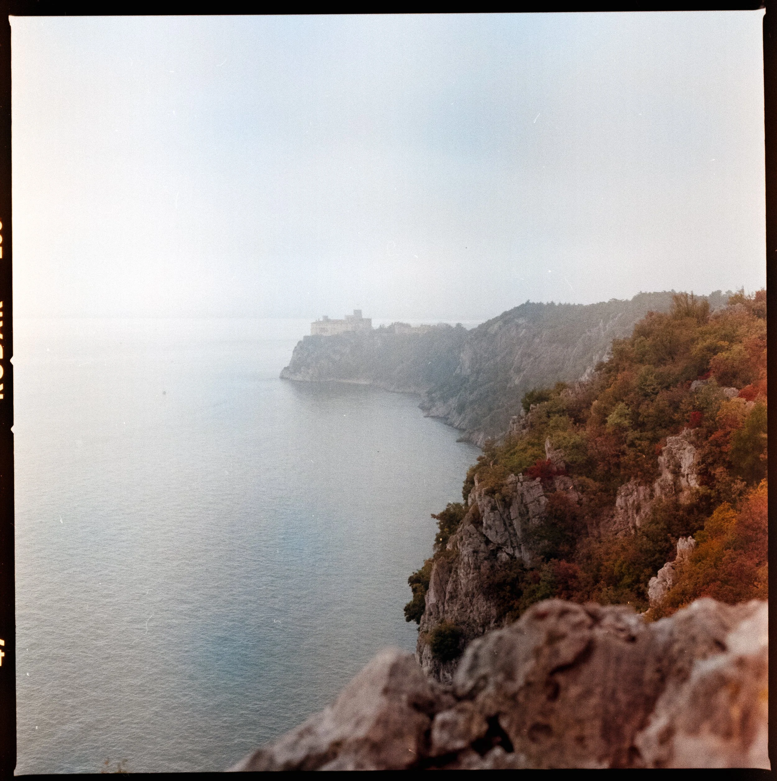 View of the Adriatic Sea and Duino Castle in the distance, seen from the rocky cliffs along the Rilke Trail near Trieste on a hazy autumn day
