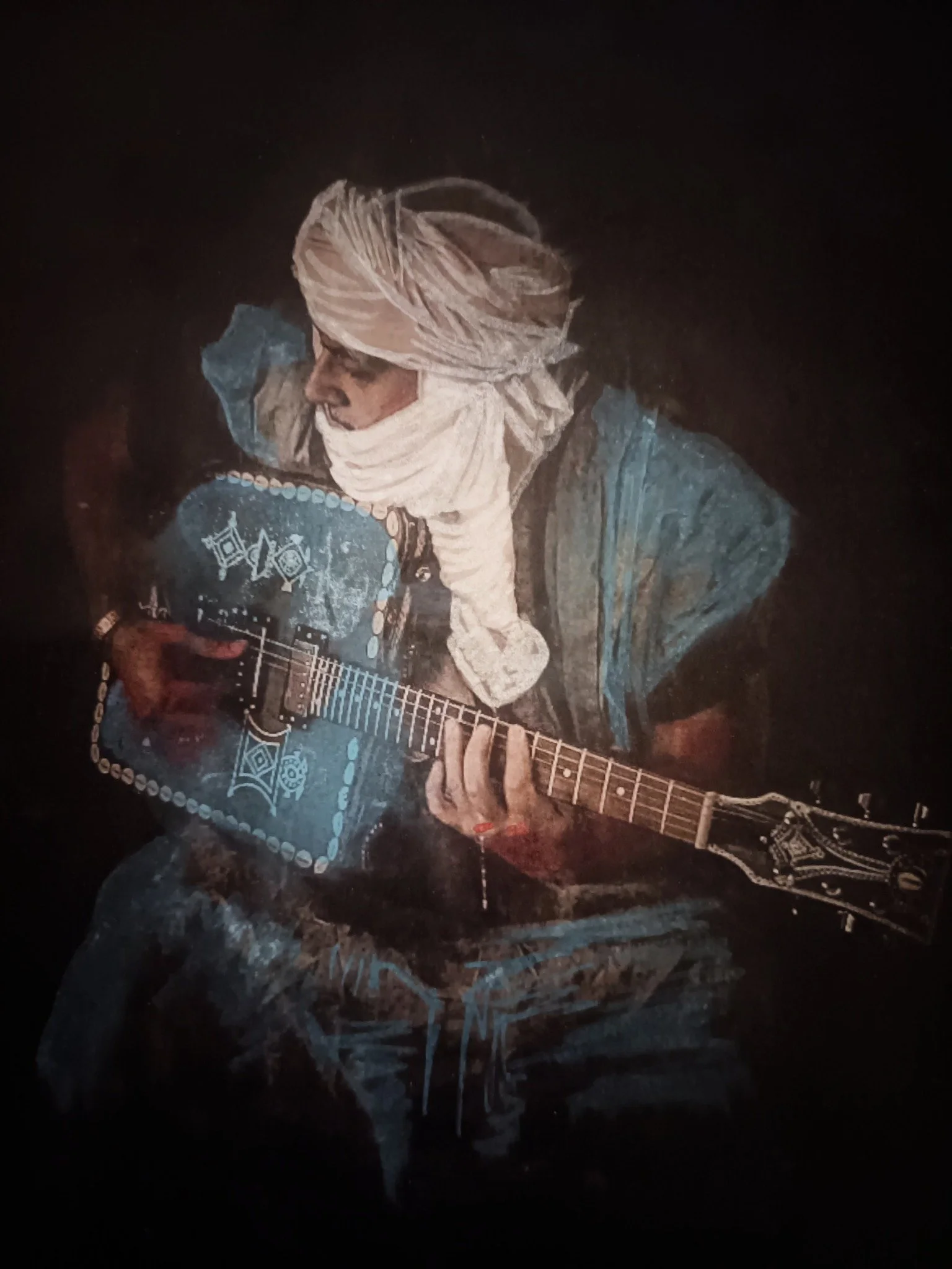 Adil Fadi playing the Gembara in blue Tuareg clothes and a white head wrap.