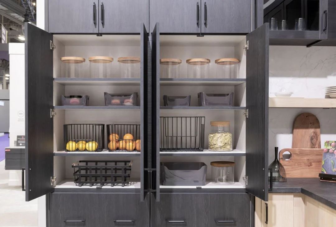 Kitchen cabinet with shelves storing jars, bowls, and fruits like lemons and peaches.