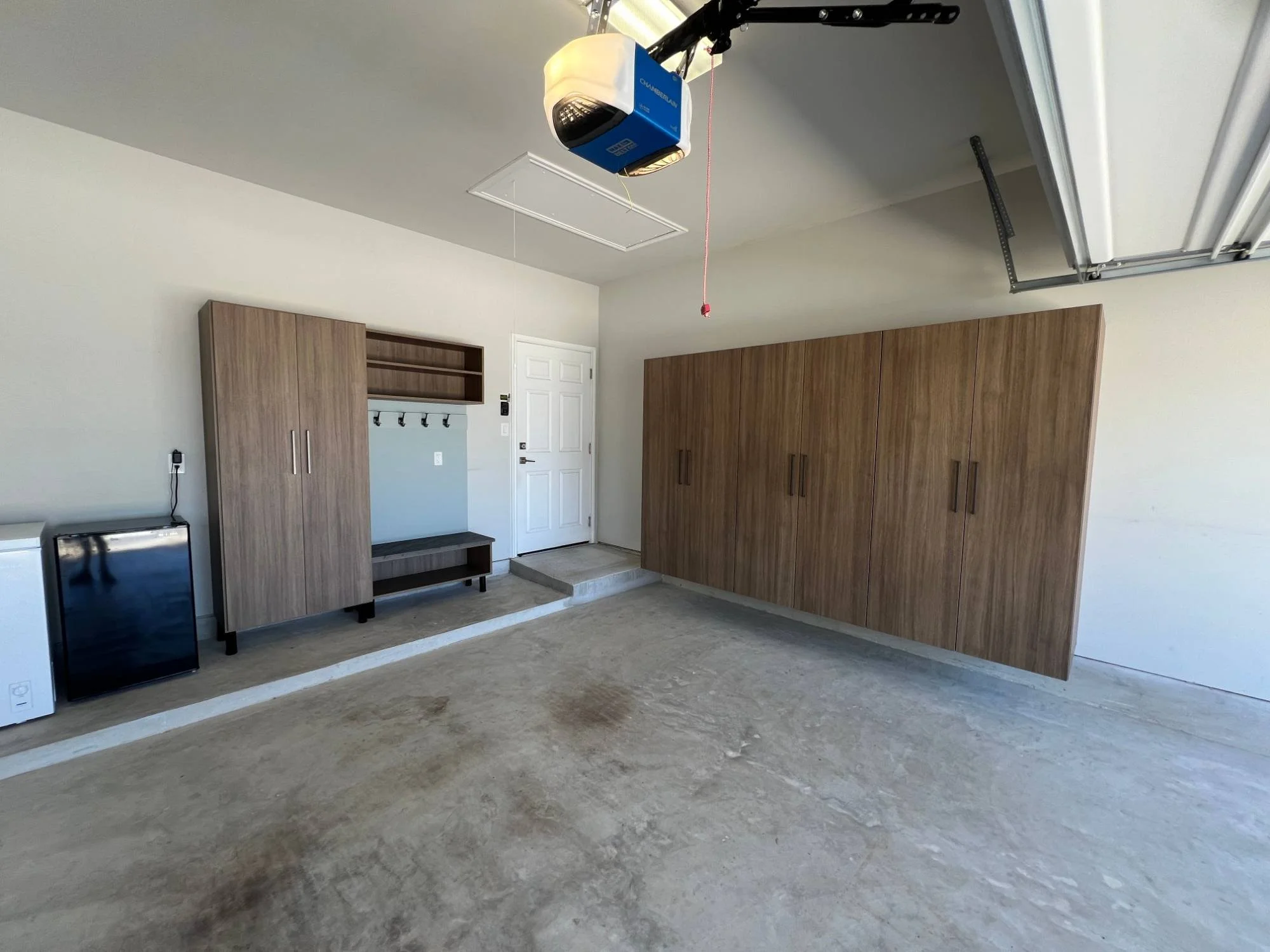 Garage with a full wall of floating storage cabinets and a drop zone at the house entry