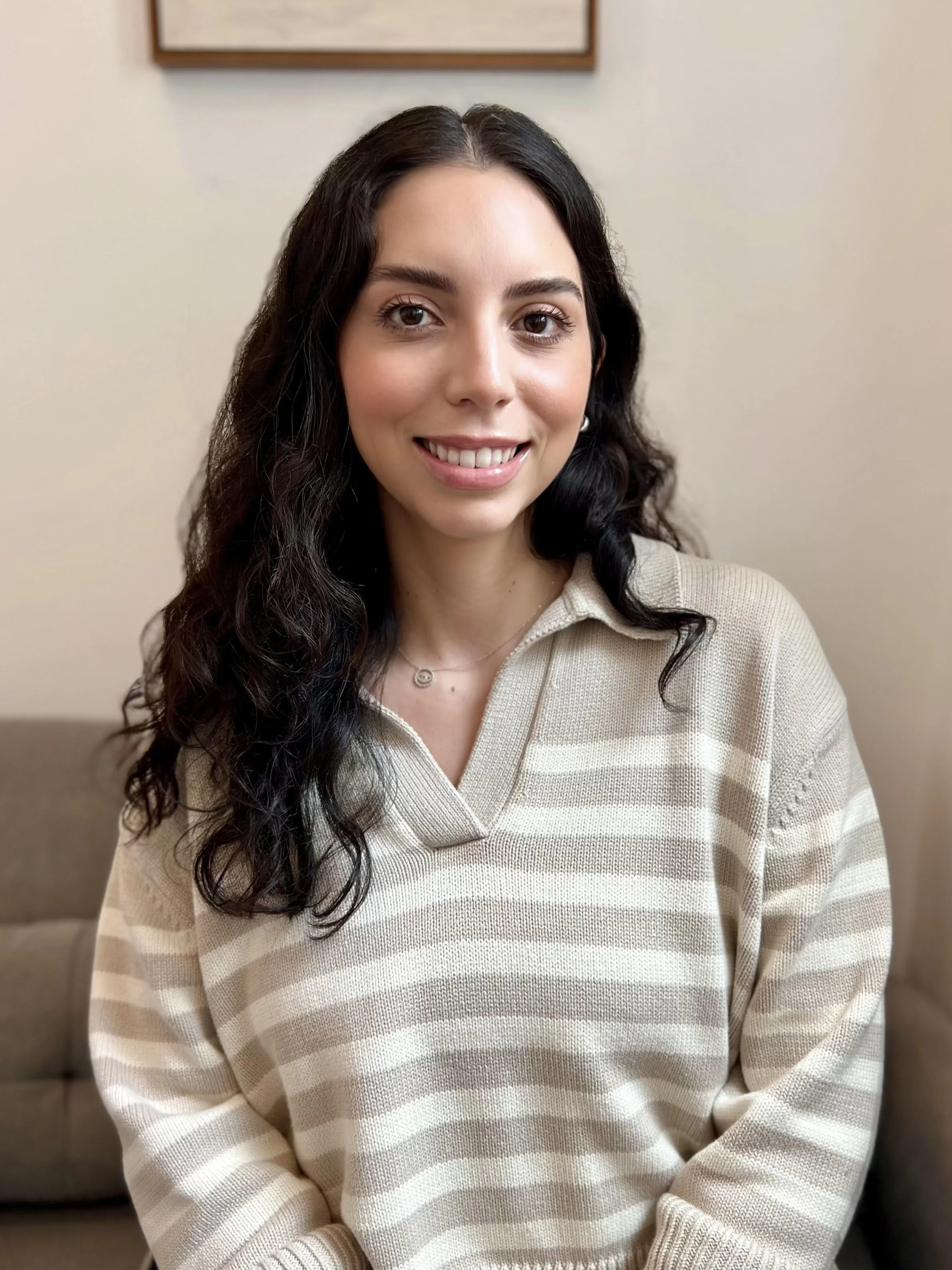 Monika Arana smiling indoors in a therapy office setting