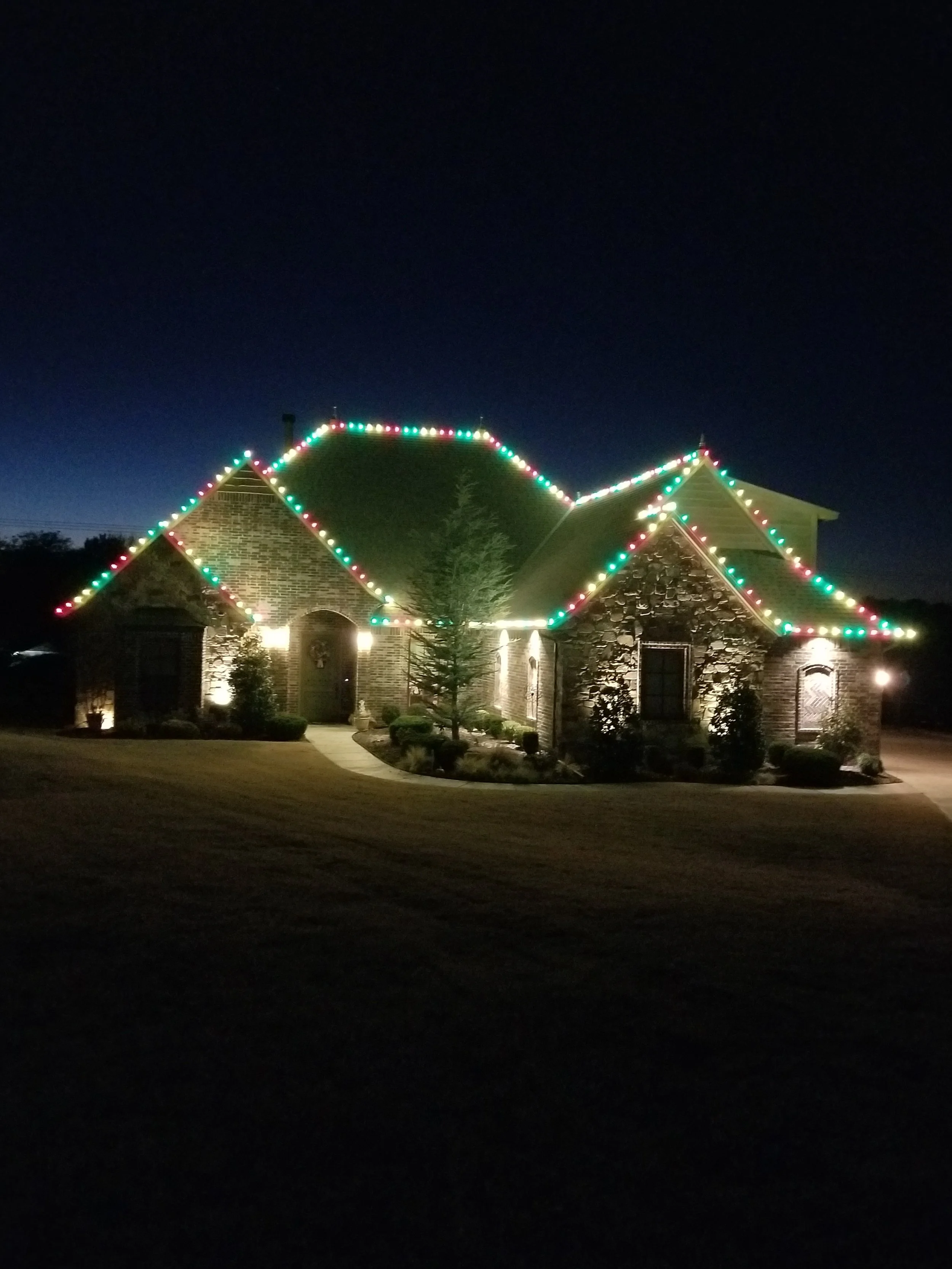 A house decorated with colorful Christmas lights on the roof at night.