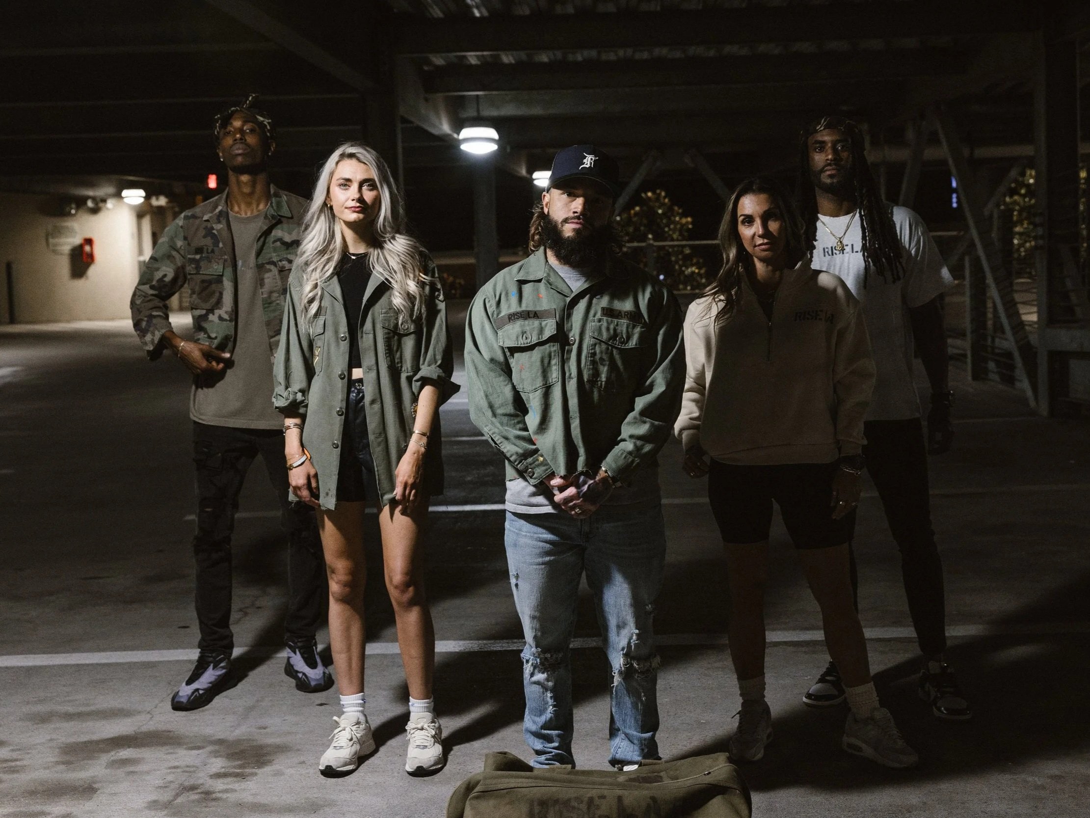 Group of five young adults standing in a dimly lit parking garage at night.