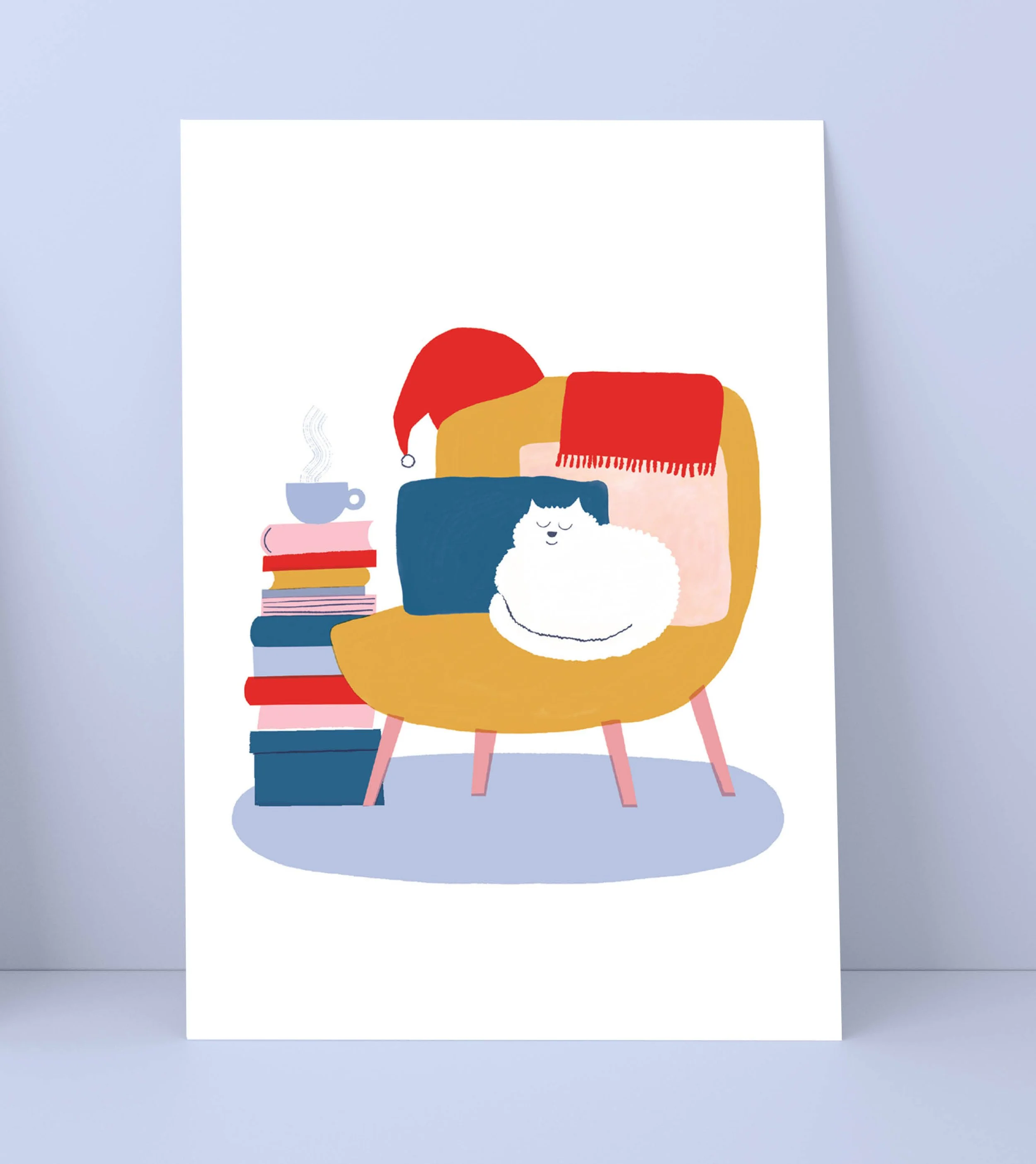 Joulukortti jossa kissa istuu nojatuolissa kirjapinon ja höyryävän kupin vieressä.