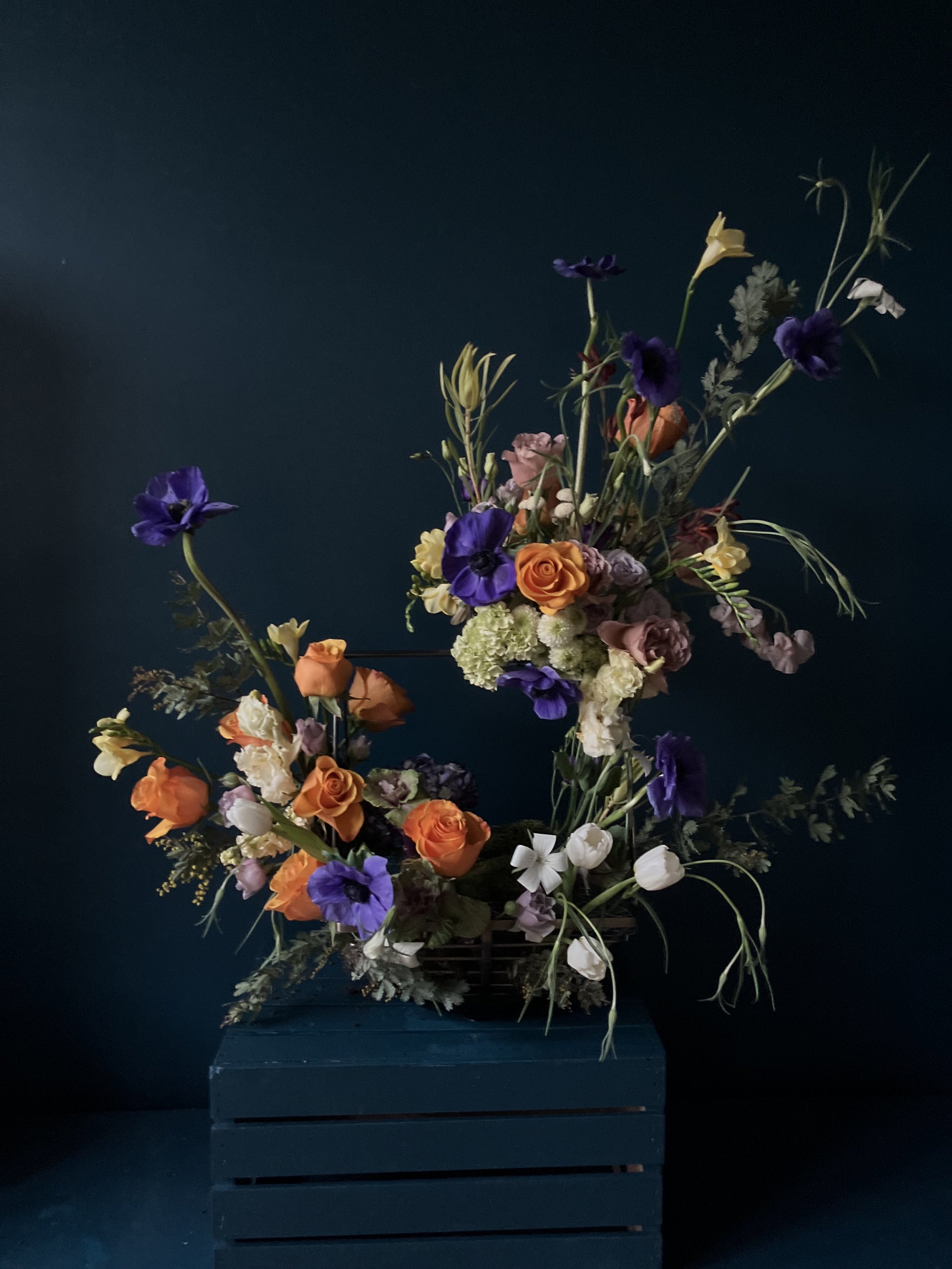 Winter floral centerpiece in contemporary elegant style that emphasizes roses, freesia and anemones