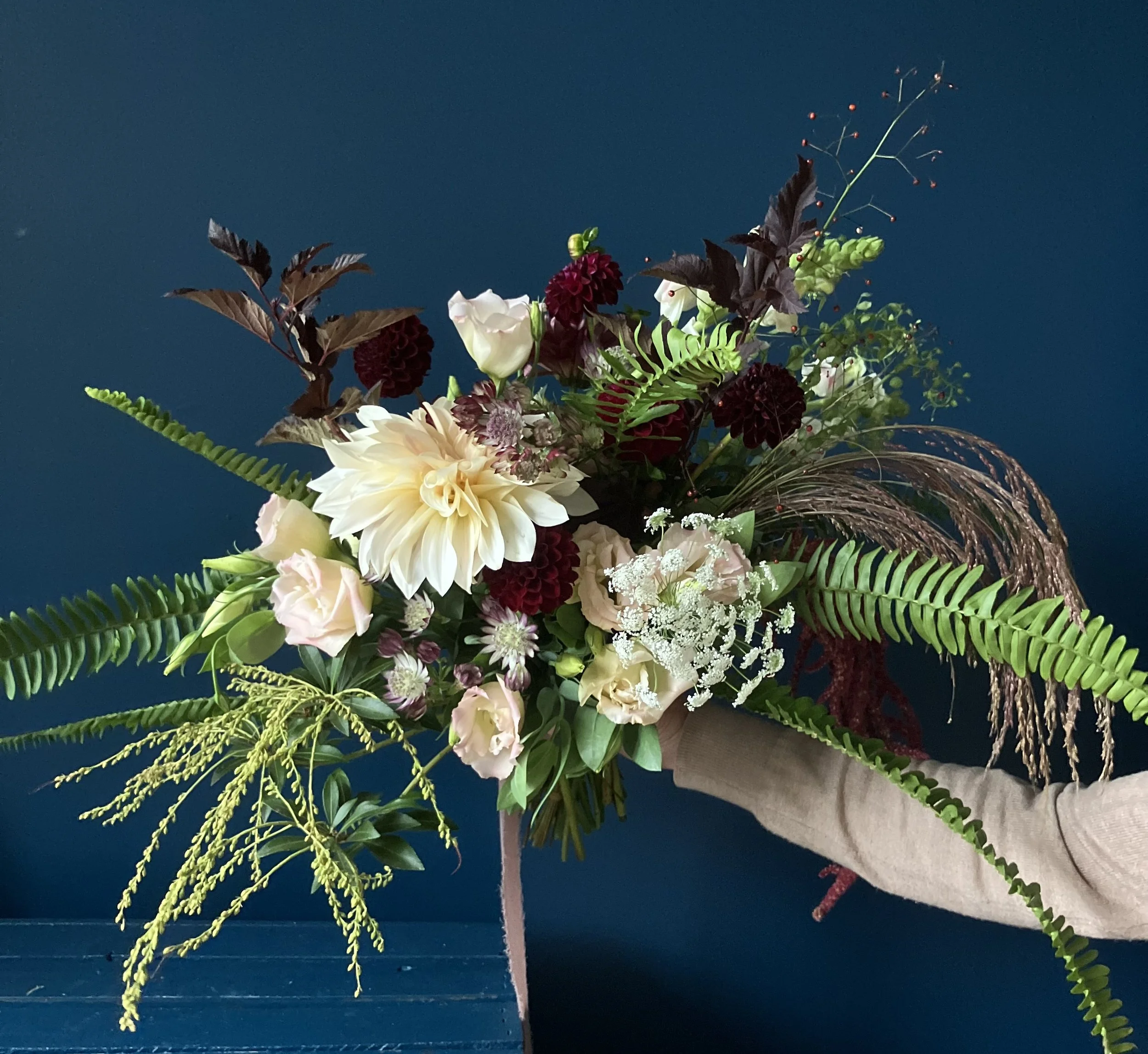 Wedding florist in Portland holding a bridal bouquet for a client made of neutral-toned dahlia and lisianthus