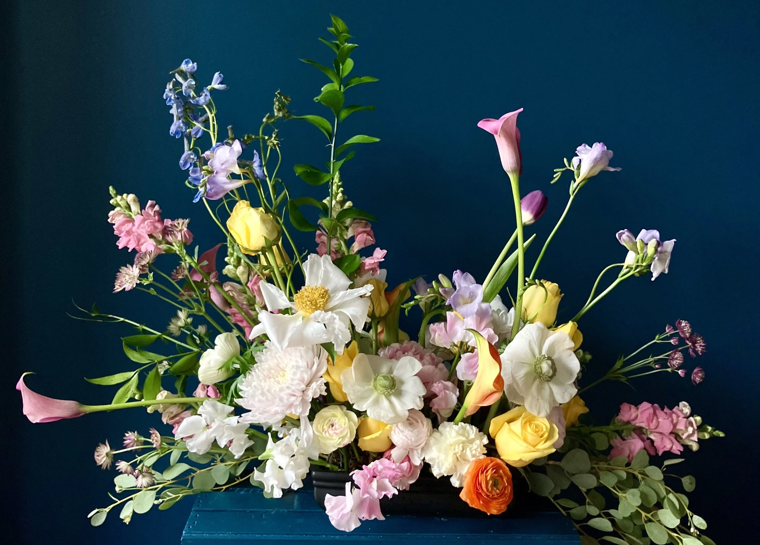 A wedding centerpiece design by a Portland OR wedding florist with roses, callas, ranunculus, mums, sweet pea, lupine and freesia