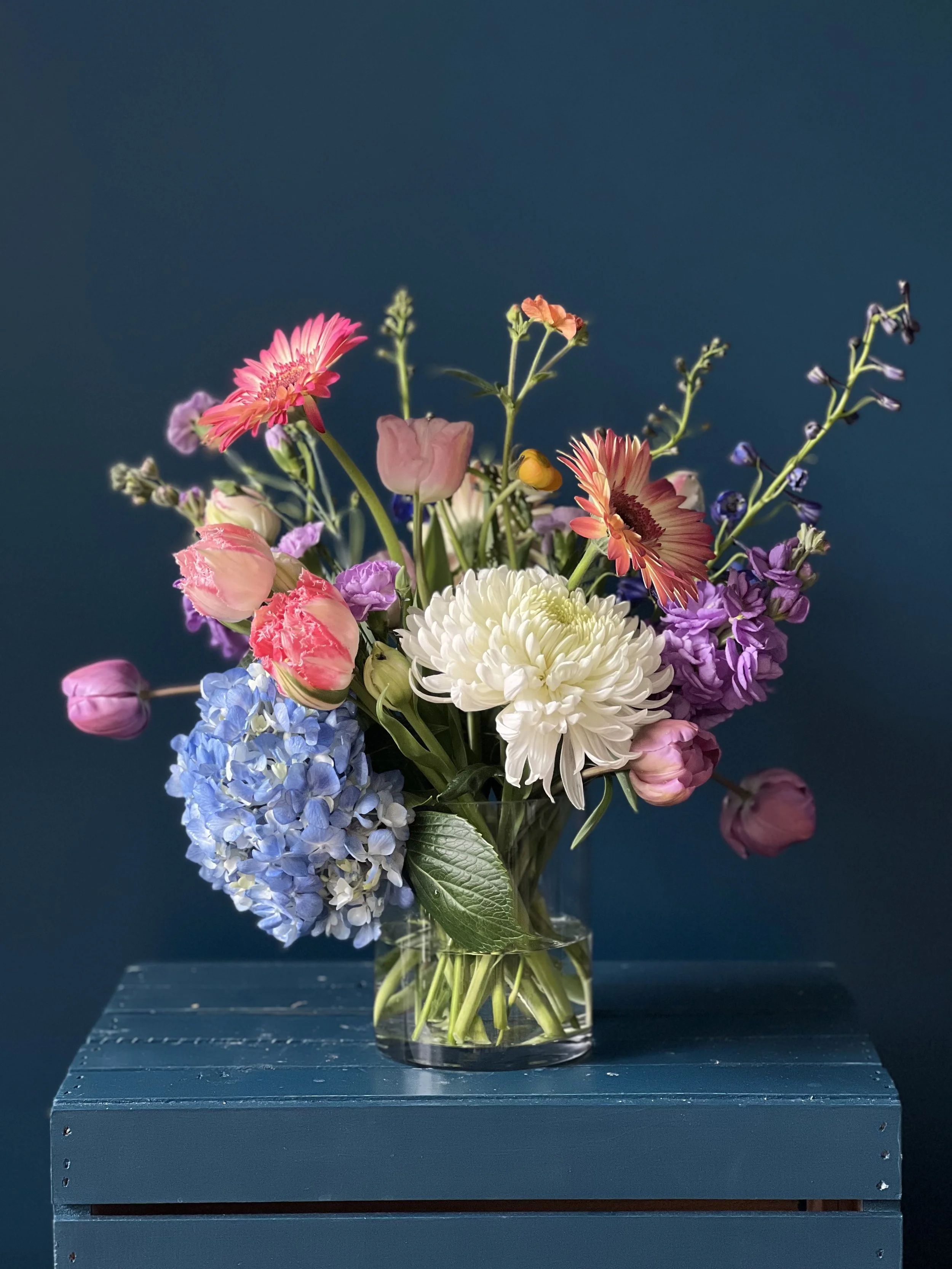 Spring flower bouquet in clear glass vase with tulips, daisies, and hydrangea, designed in our Portland florist for Mother’s Day delivery