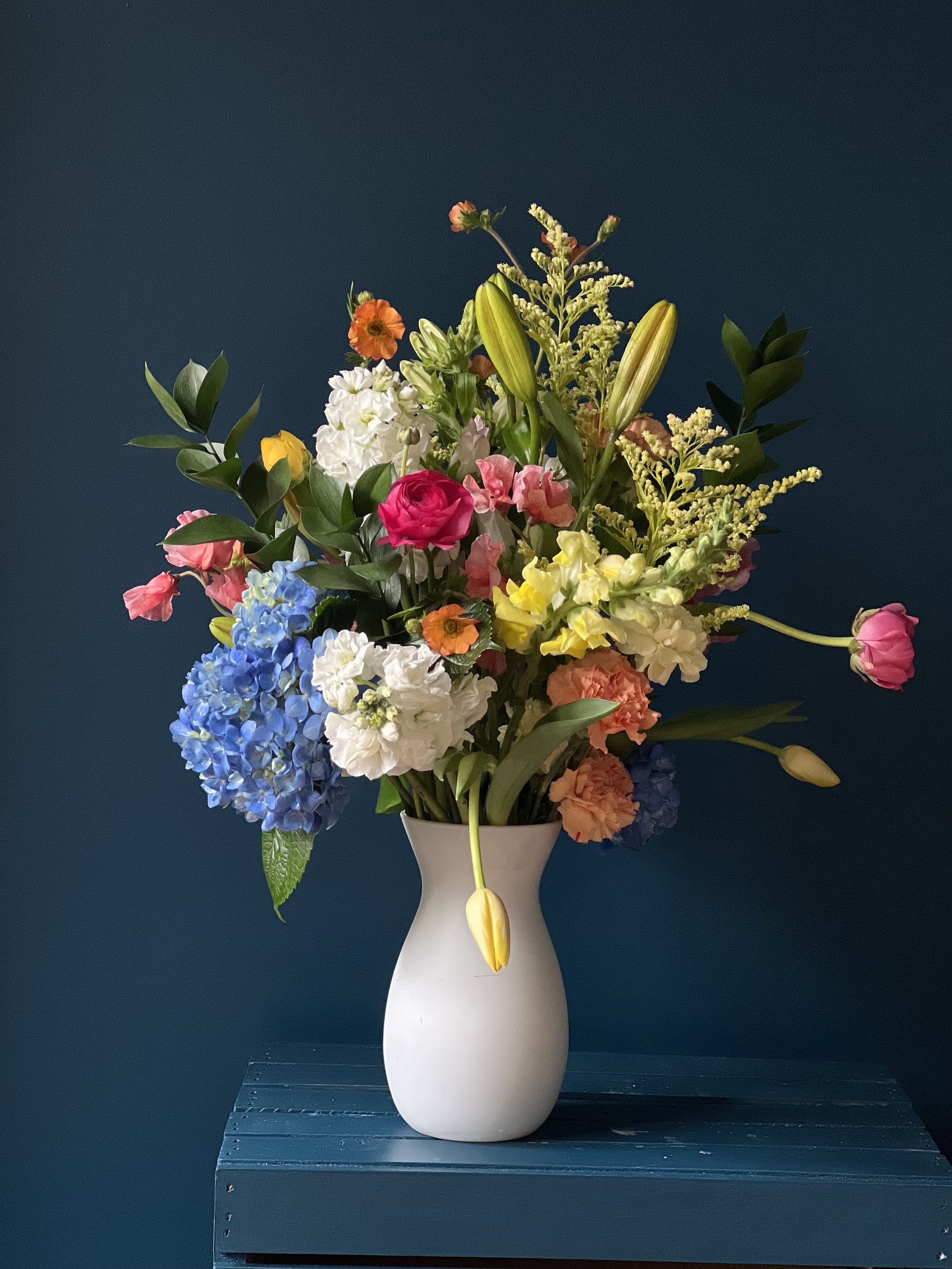 A mega-bouquet of orange lilies, tender coral peas, pink ranunculus, garden geum & carnations