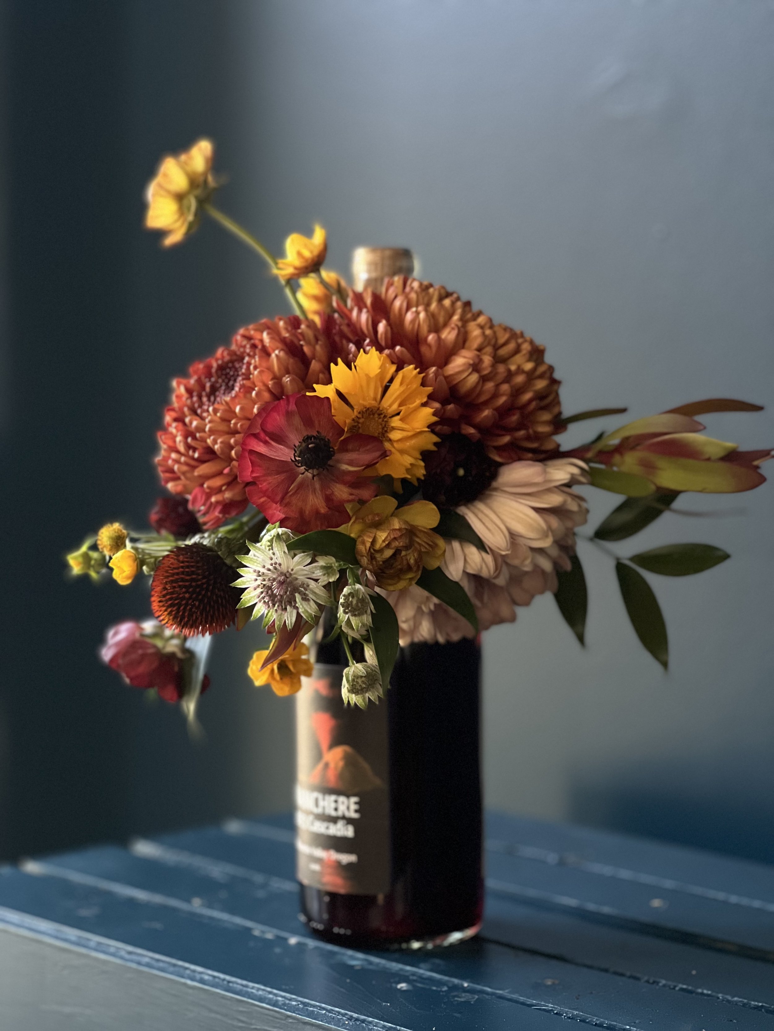 A masculine, neutral-tone flower gift of a bottle bouquet on a rose wine