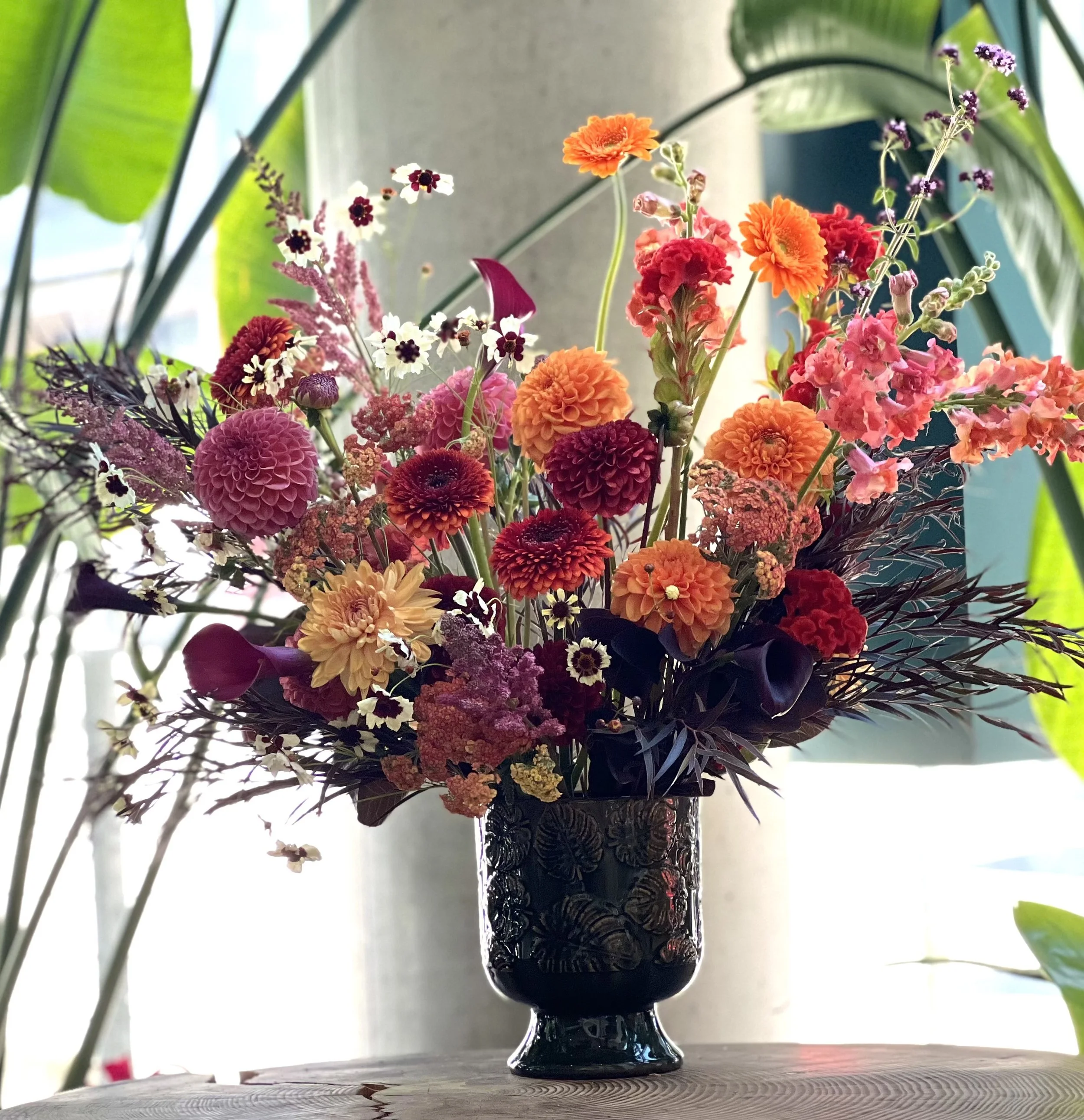 Sunset-colored dahlia design with supporting flowers in a vase, delivered and placed in a reception at a local Portland business