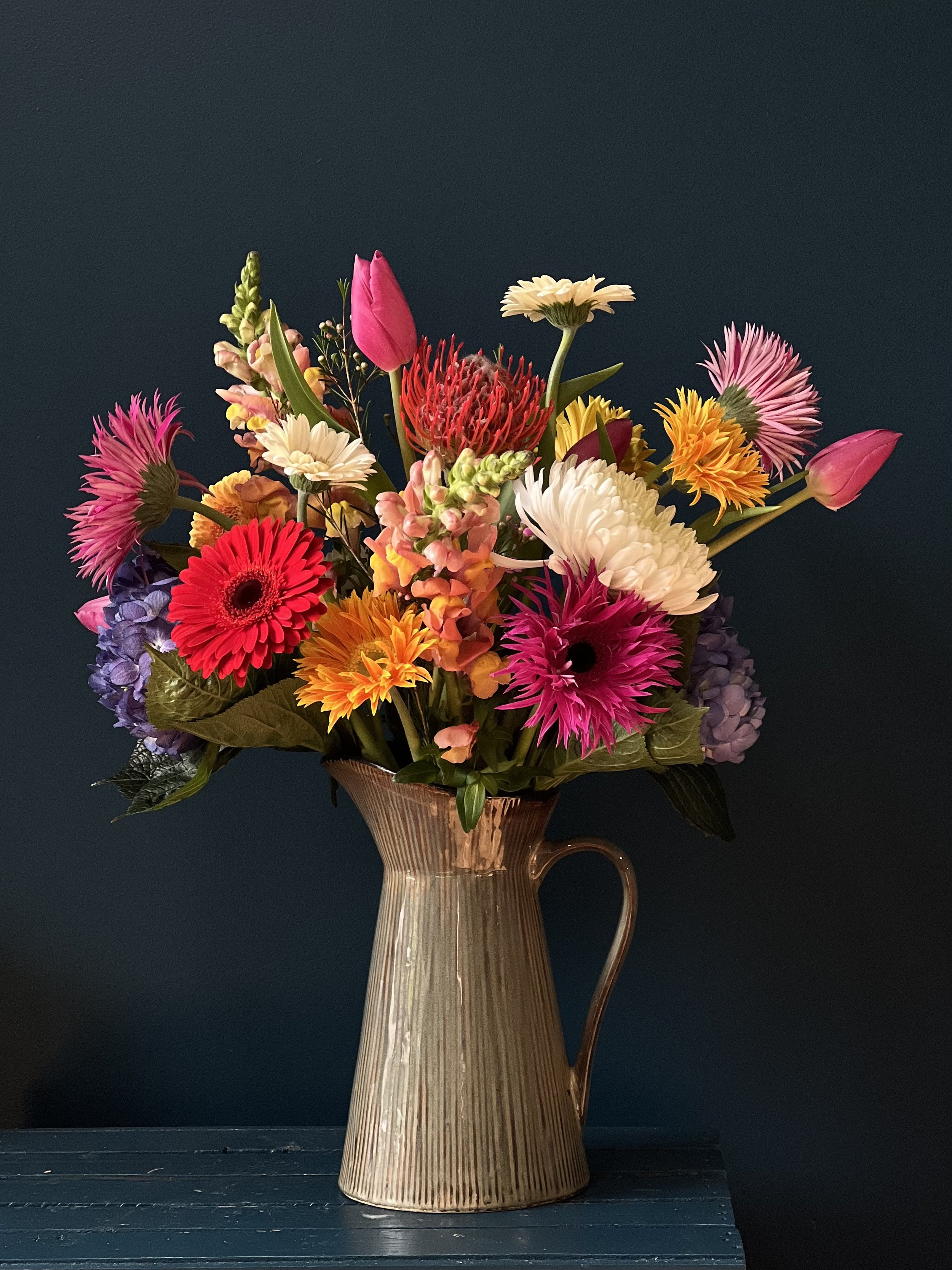 Multi-colored sphere of bright blooms in a pitcher arrangement, made for Portland flower delivery