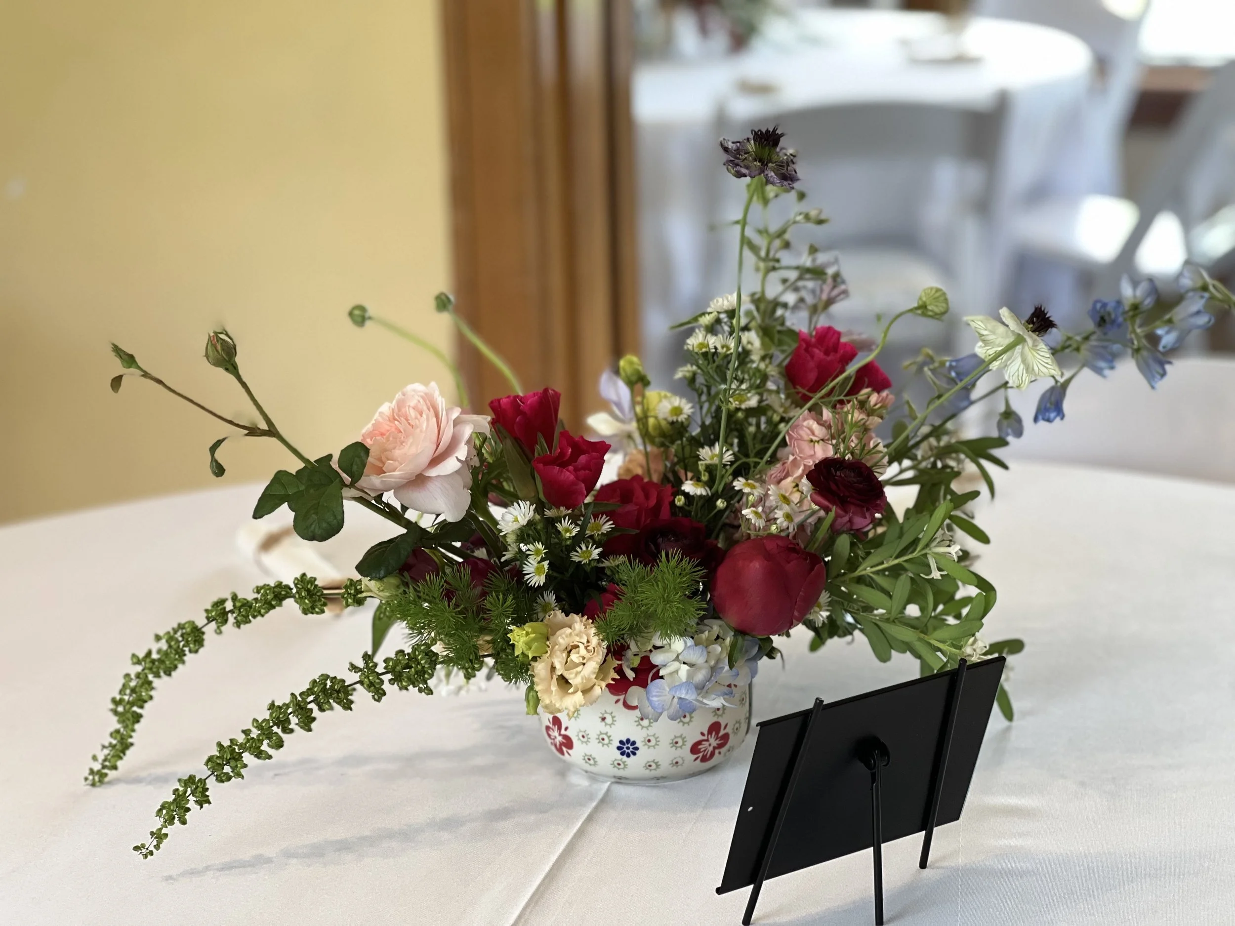 Table arrangement for a Portland wedding in a unique custom vase, with roses and peony and foliage, designed by Portland wedding florist