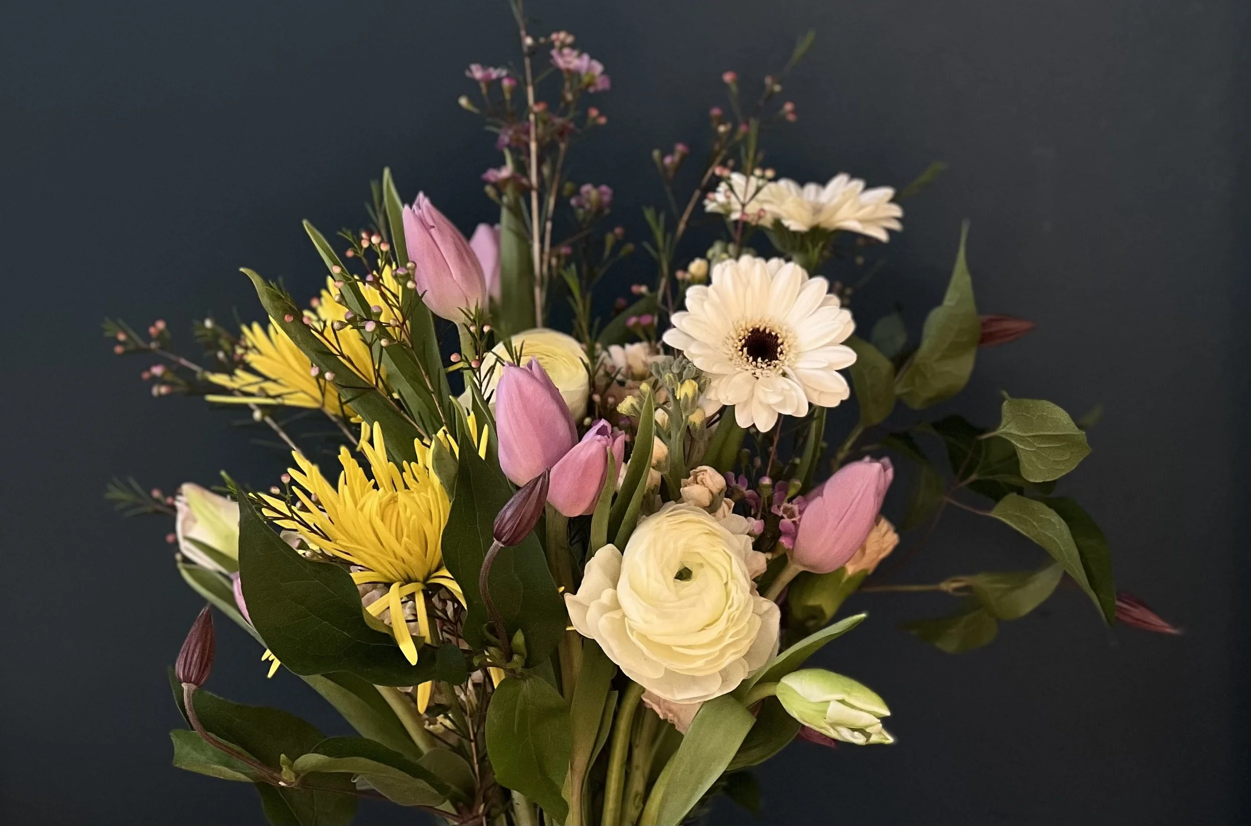 Close up of sympathy blooms on dark background arranged by a Portland Oregon florist