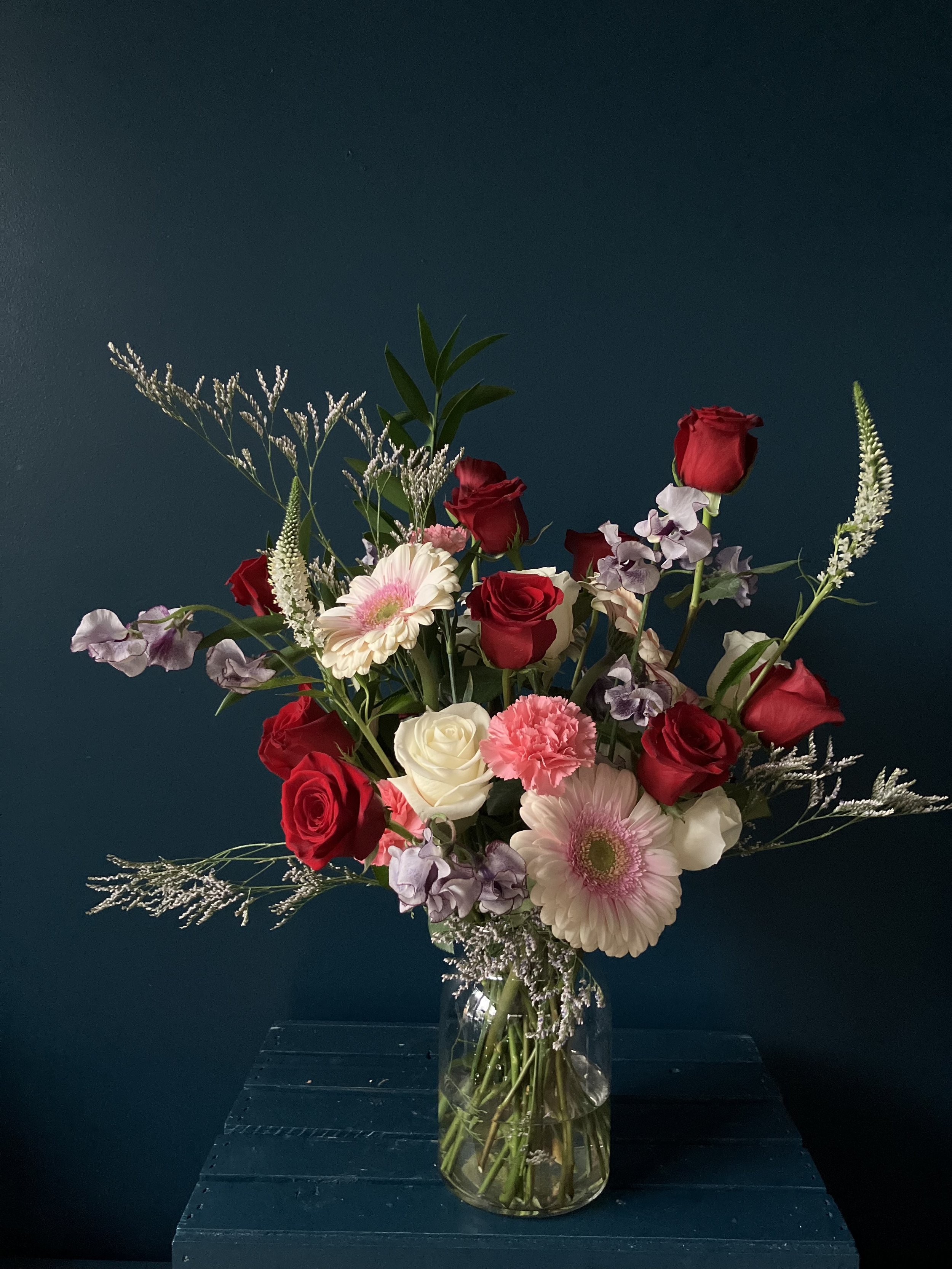 Elegant and romantic rose and daisy arrangement for Valentines, including swooping sweet peas, designed by N. Portland's premier florist