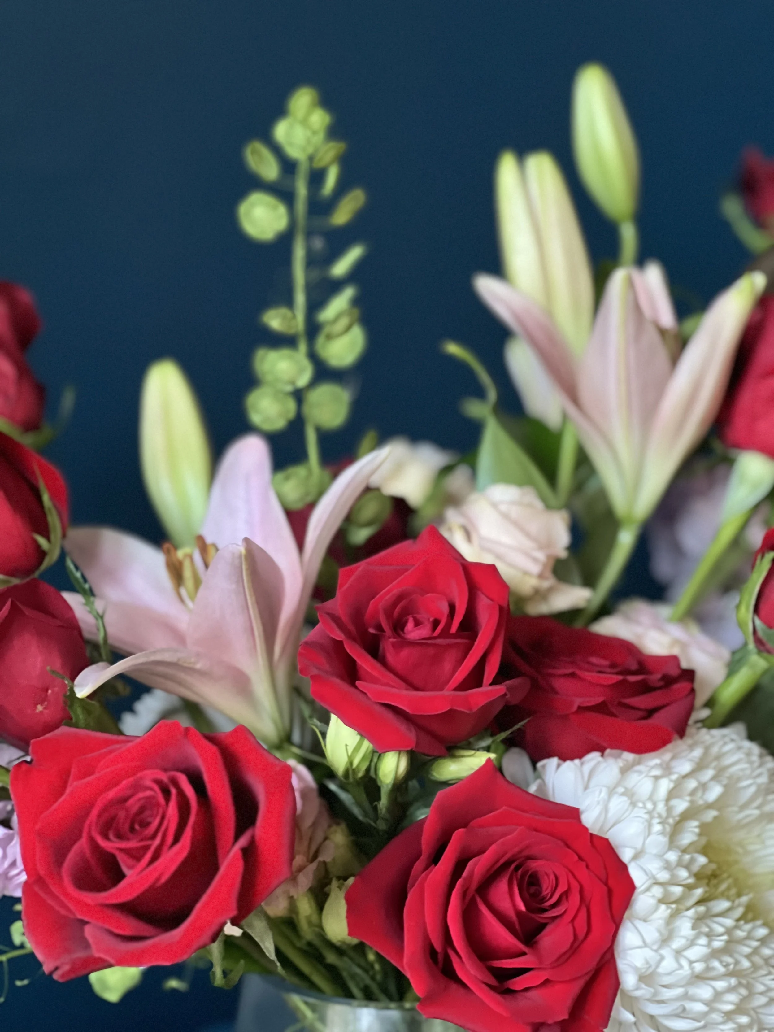 Close up of Valentine's Day flower arrangement with red roses, pink lilies, and lavender accents in a clear vase, designed by a Portland florist