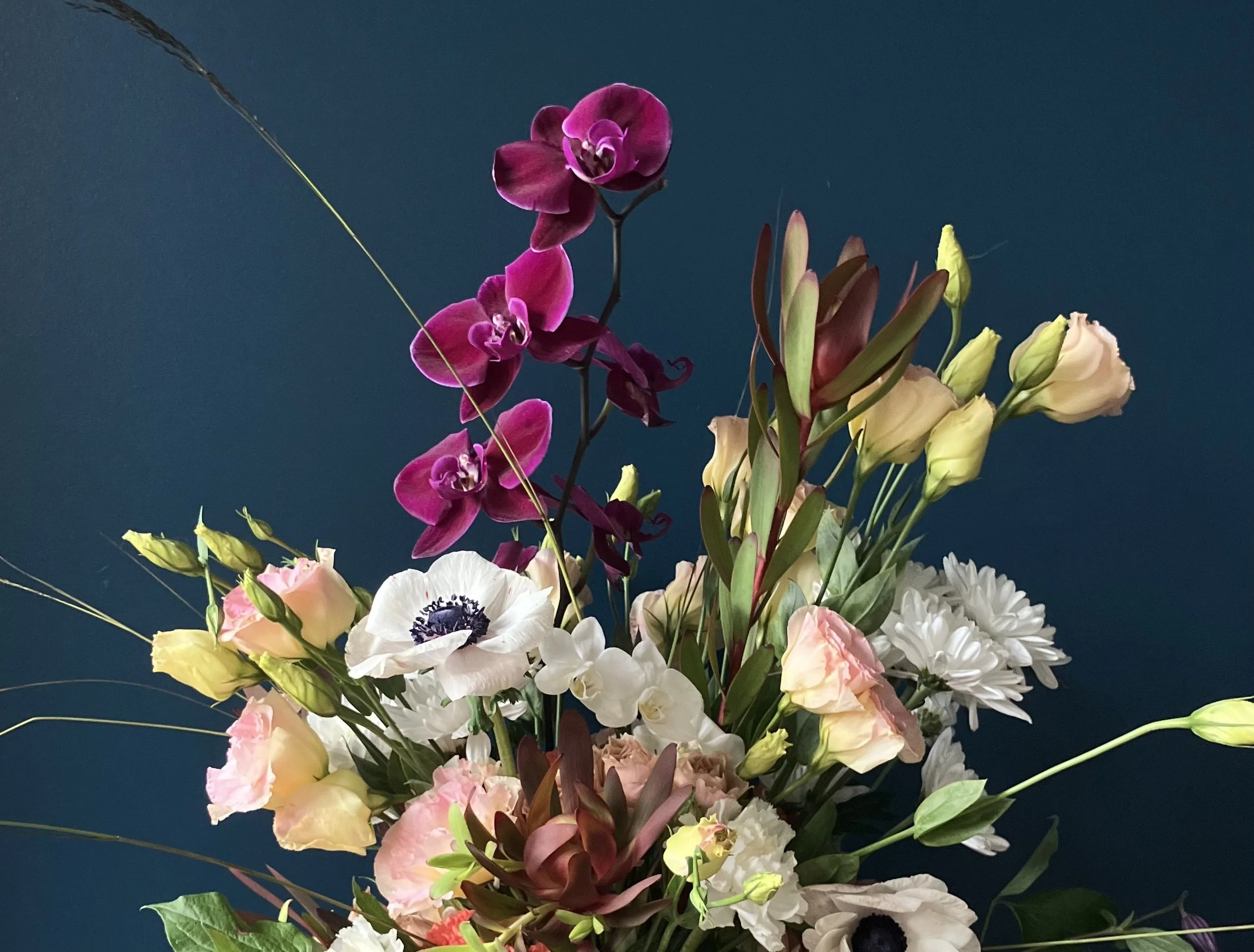 Closer detail on orchid, white anemone, and blushy lisianthus against dark background before Portland delivery