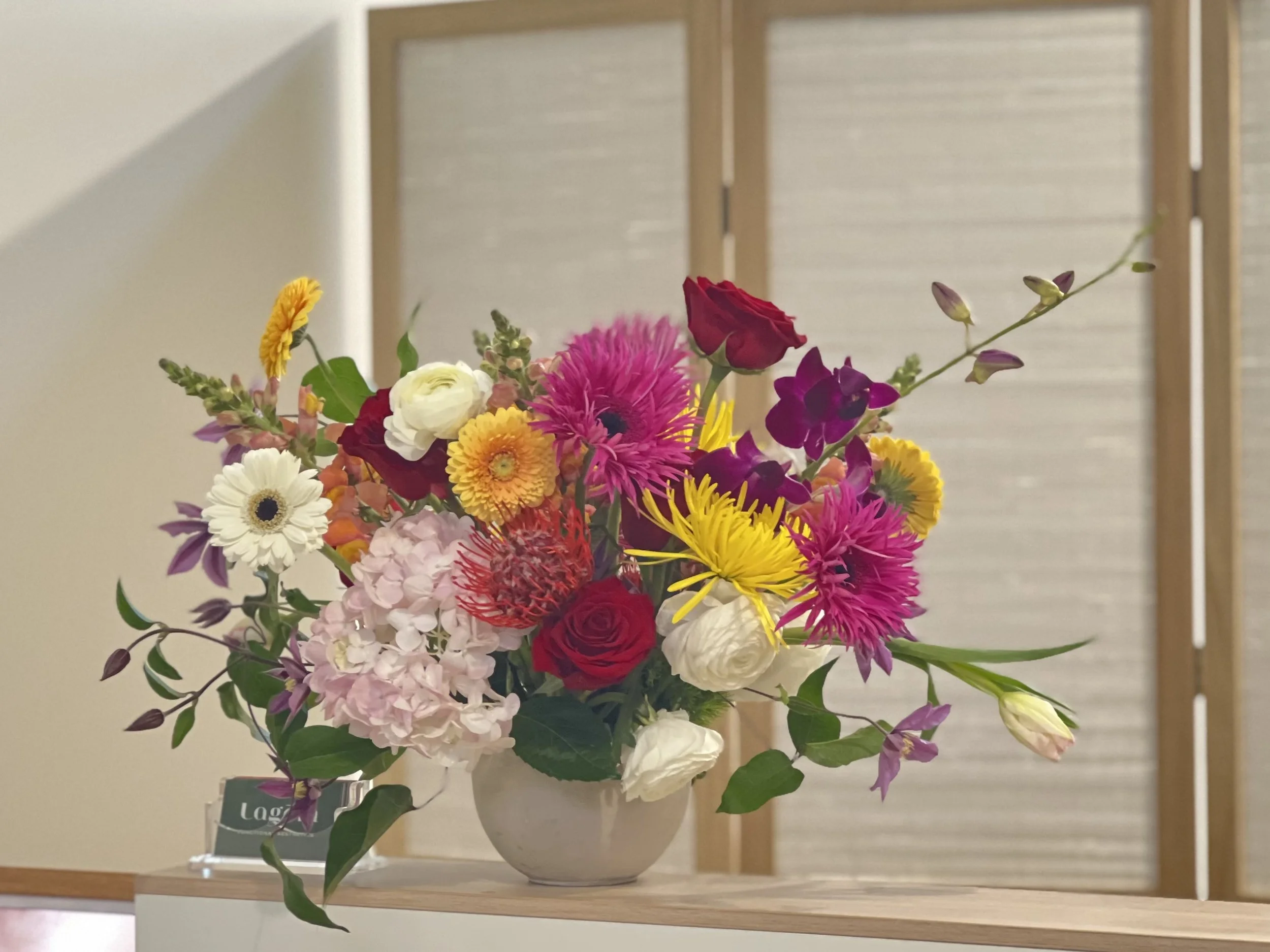 An arrangement of white, pink, red and yellow blooms in a lobby, designed for a Portland floral subscription at a local business in North Portland