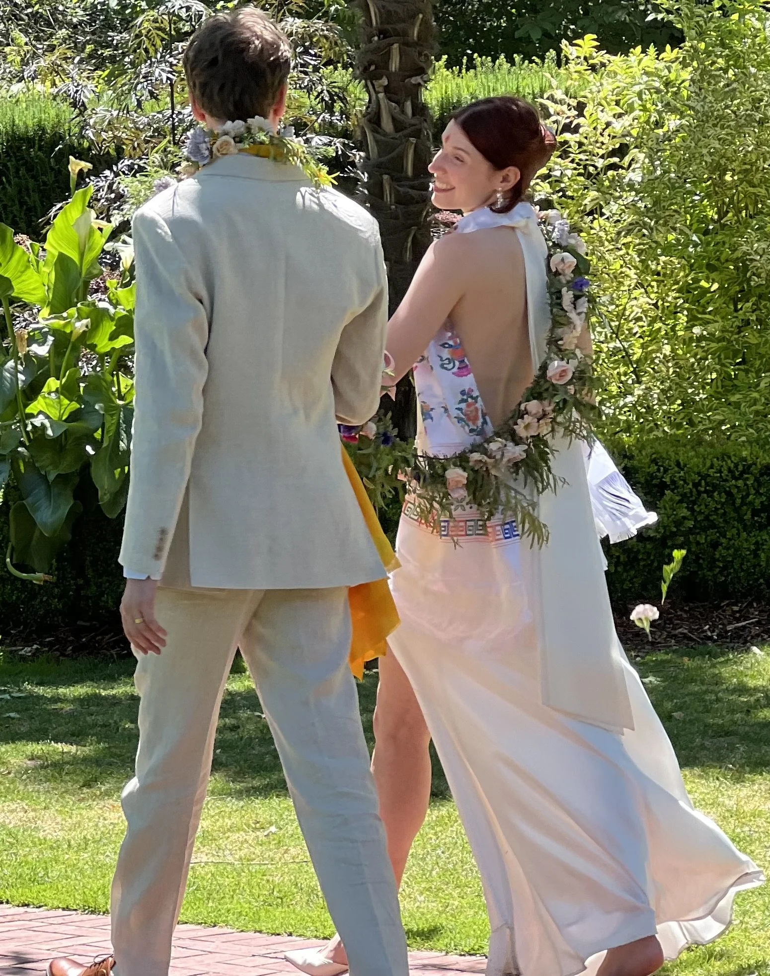 A bride and groom at a Portland wedding at the Rose Garden walking with a flower garland designed by Portmanteau