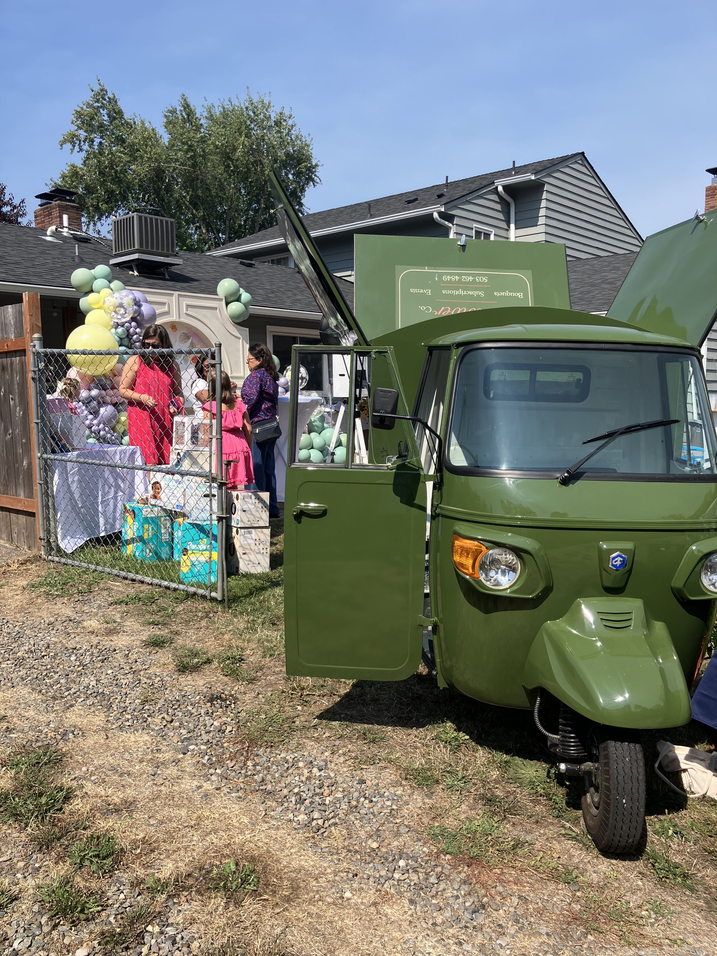 Mobile florist with a truck of DIY blooms parked at a private baby shower event in summer in backyard with people standing