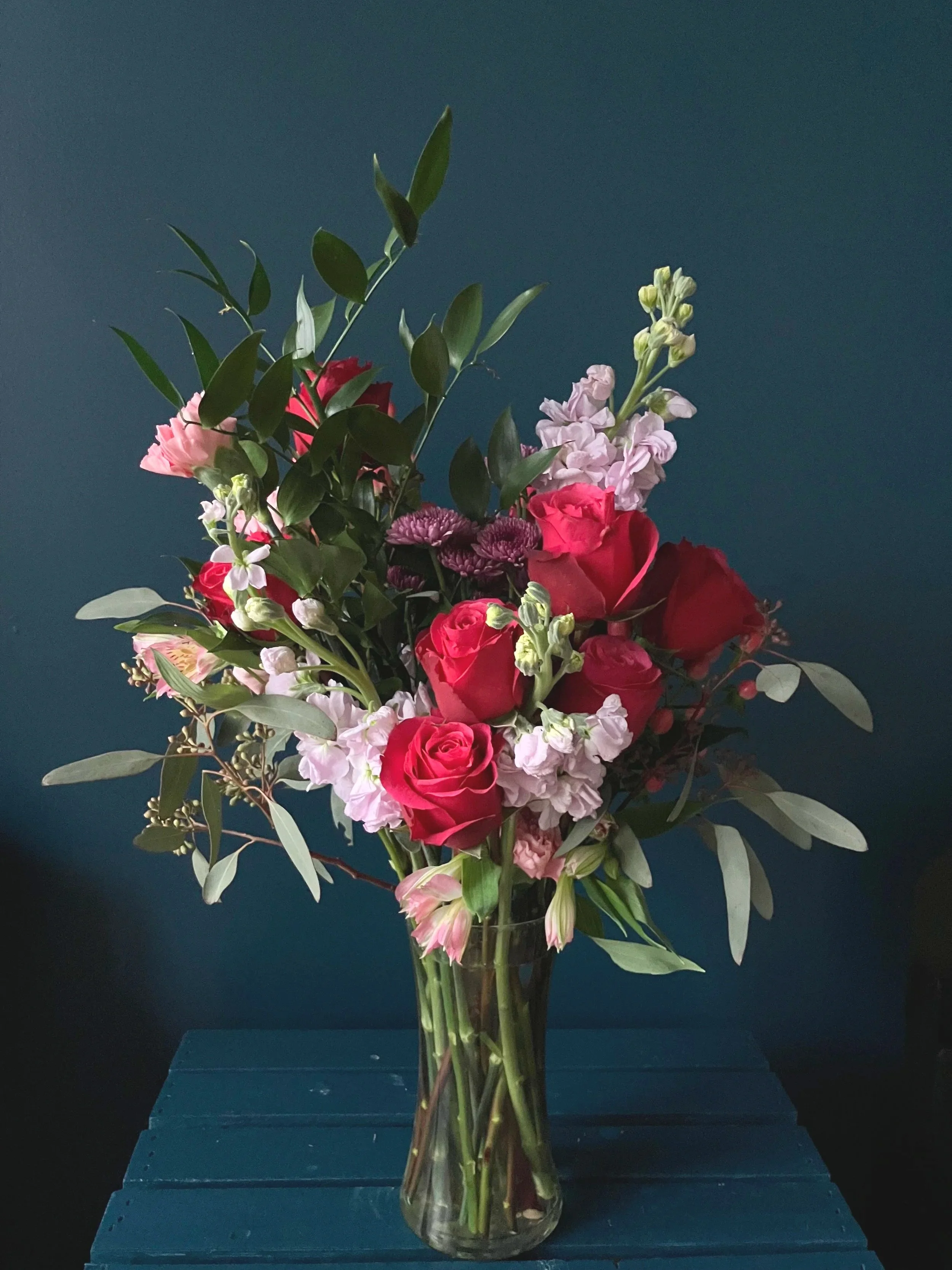 Classic Valentine's bouquet made in Portland, featuring red roses, purple stock, pink carnations, and eucalyptus