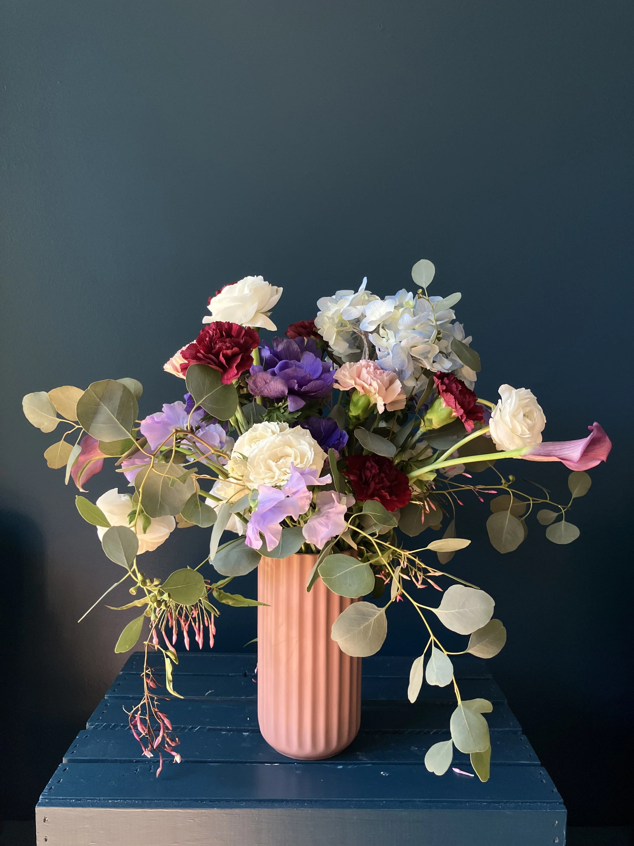 Mother's Day arrangement with hydrangea, white roses, pink calla lilies and sweet pea, purple anemone, carnations in a vase