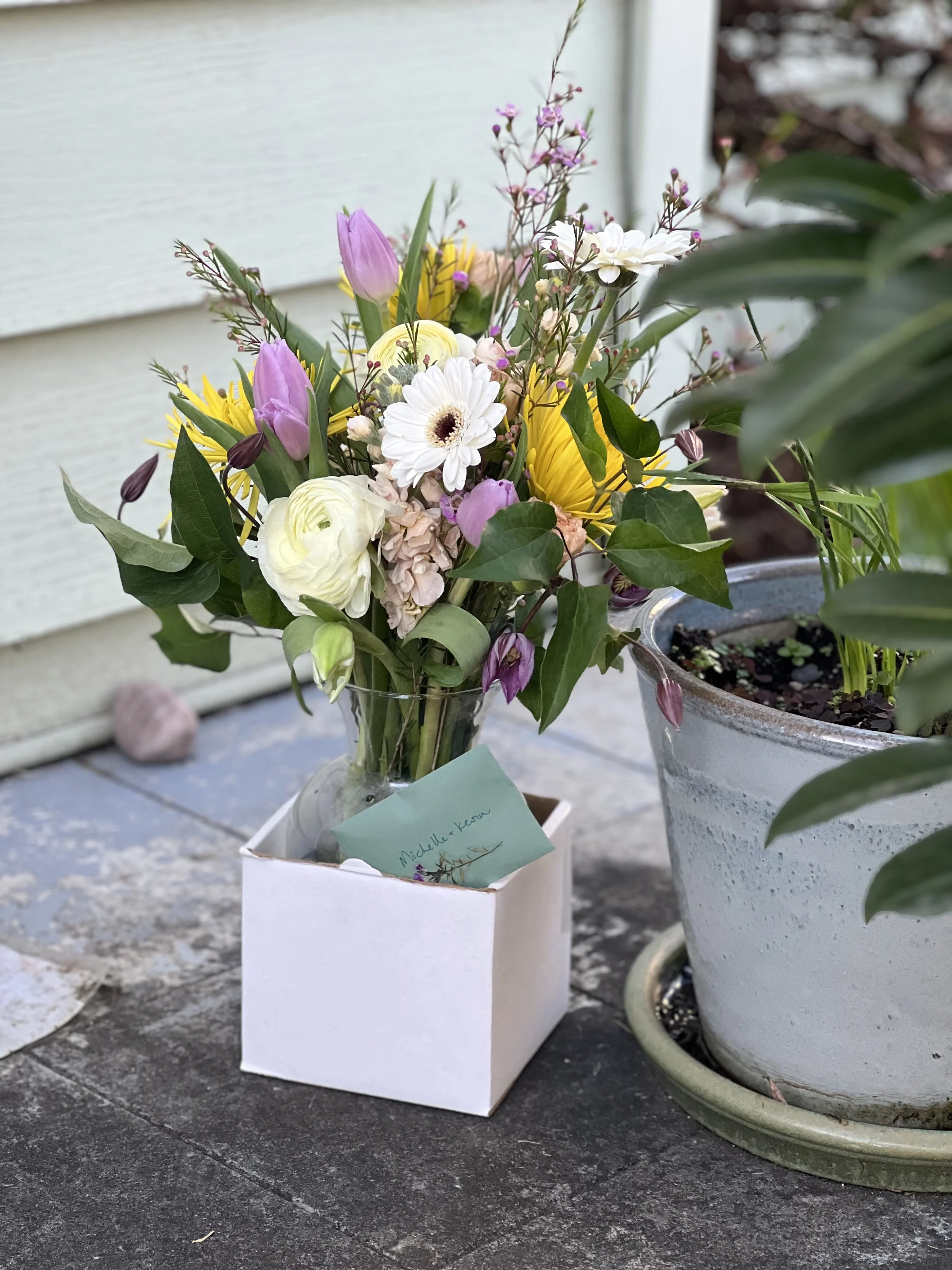 A soothing, neutral-tone sympathy arrangement outside a North Portland home where it was delivered next to a potted plant