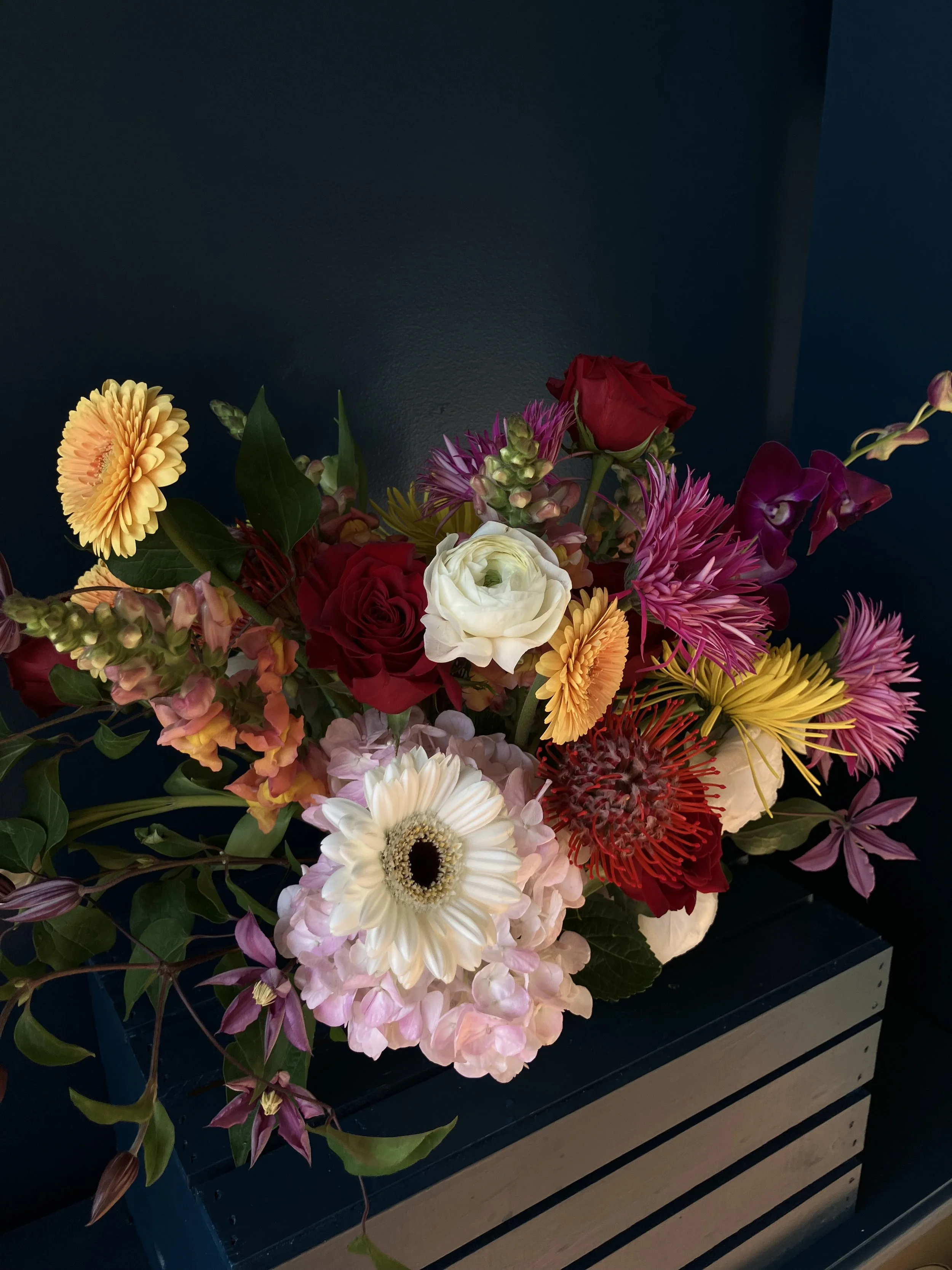 Artful, fine art bouquet in vessel, featuring vibrant pink, red, and white blooms in a low sustainable vase, expressing solidarity with immigrants, designed for Portland flower delivery