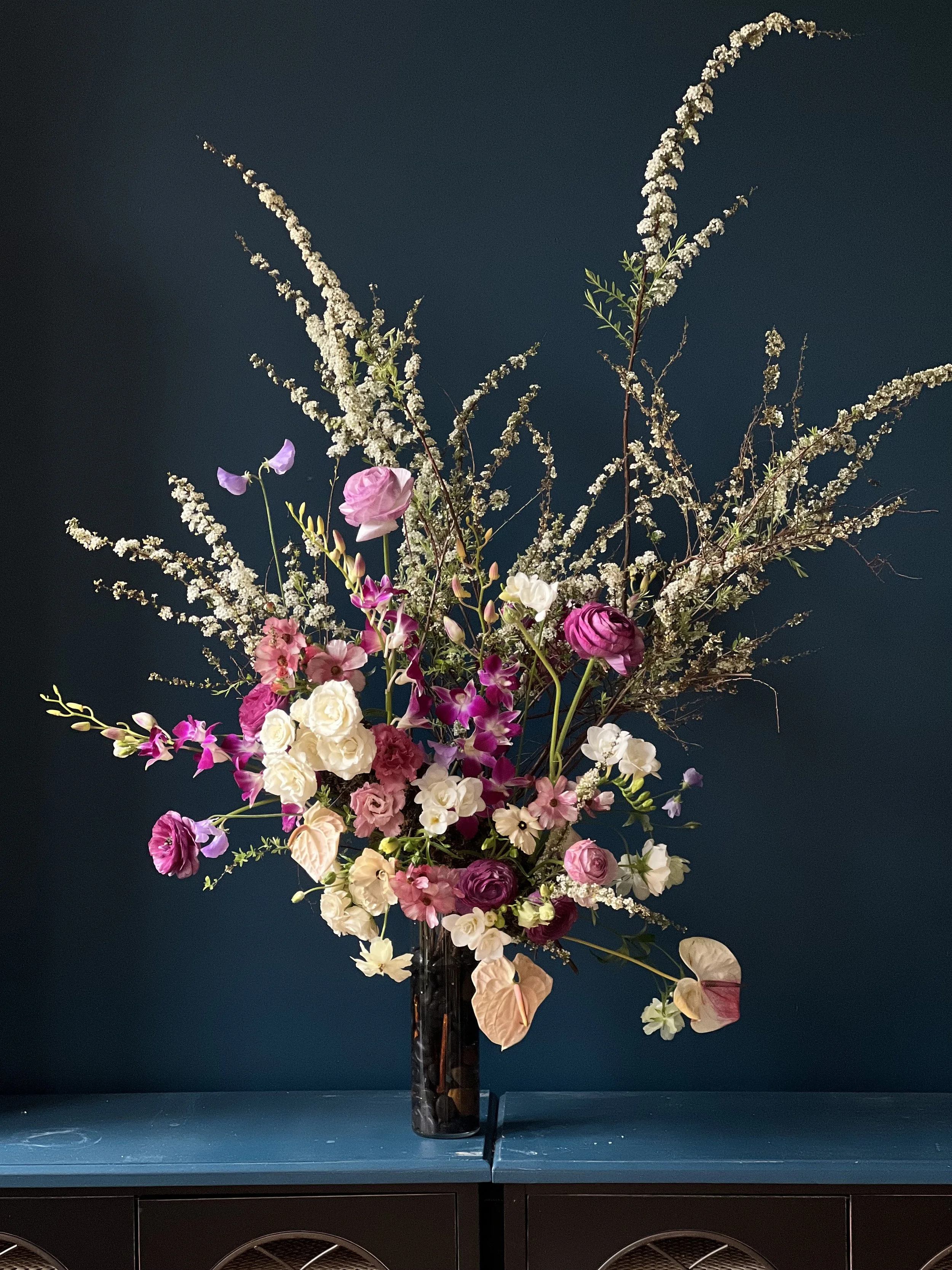 A wedding centerpiece in purple and white with orchids, ranunculus and spring blooms of spirea, designed by a Portland, OR wedding florist