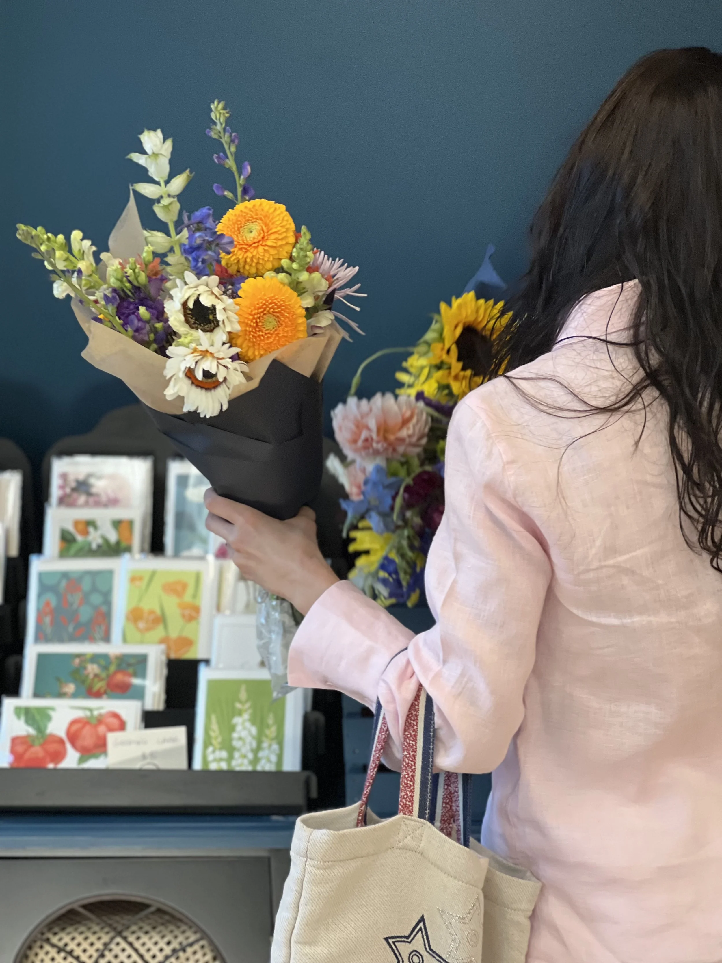 A customer seen holding two hand-tied, wrapped bouquets with cards behind in Portmanteau's flower shop, NE Portland