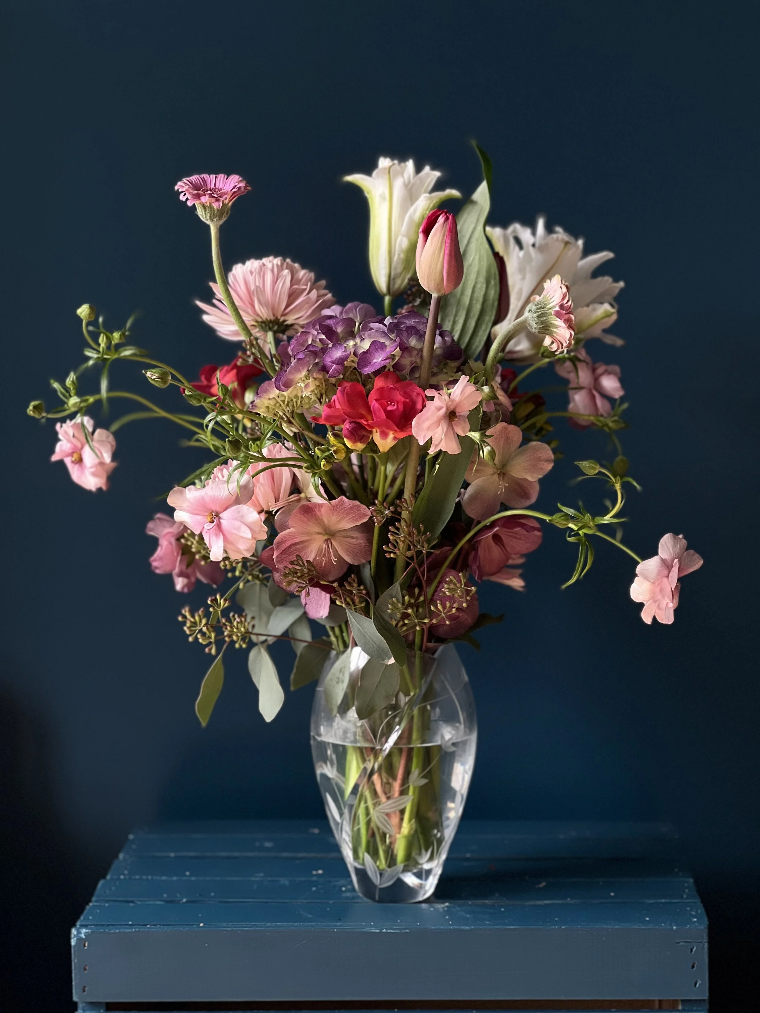 Large spring bouquet with blush mums, red tulips, freesia, pastel zinnias, butterfly ranunculus, white lilies, and a purple hydrangea by a Portland florist