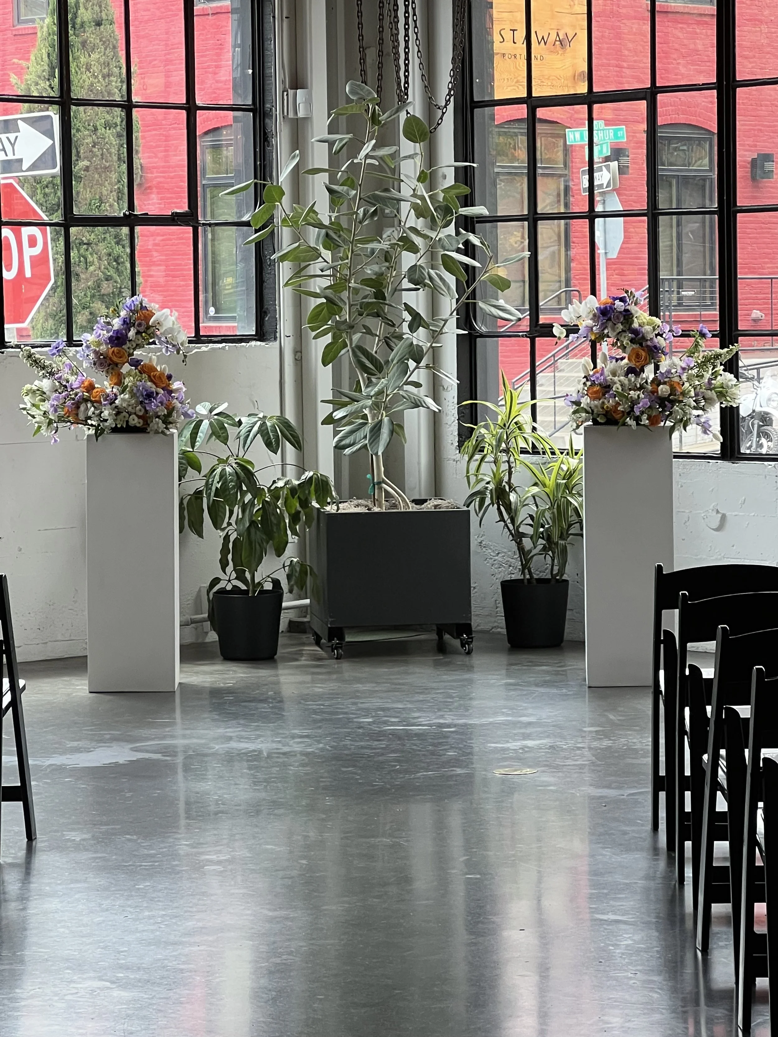 Two wedding arrangements as swans on pedestals in the ceremony area, blooms designed for a Portland Oregon wedding