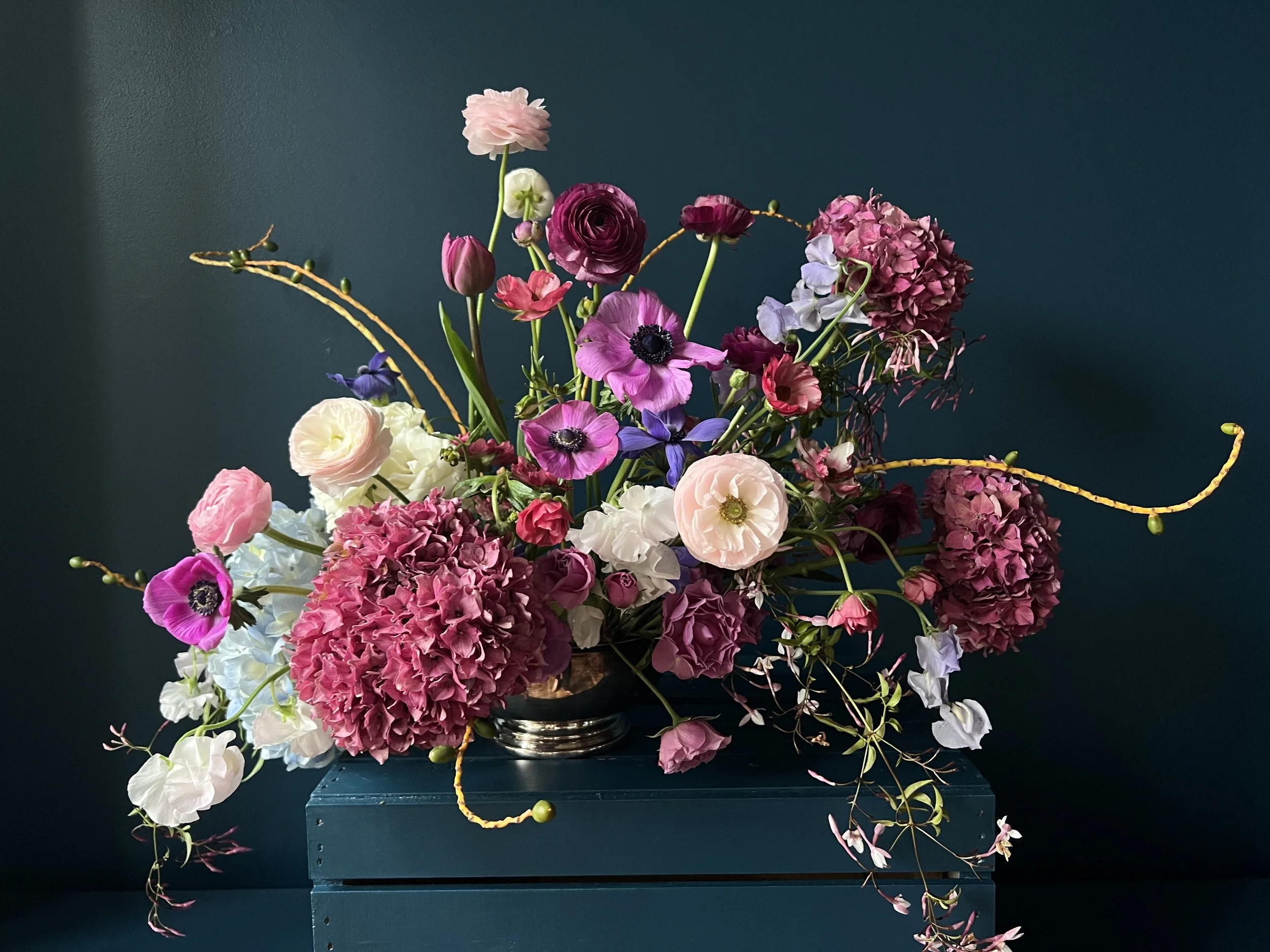 A wedding centerpiece in pinks and deep reds with spring ranunculus and anemone, made by our wedding florist Portland