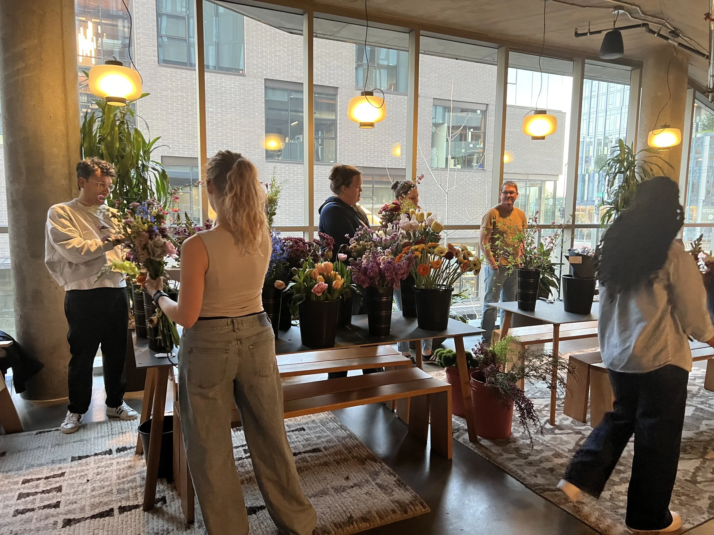 A bloom bar in Portland with people picking fresh flowers displayed in French buckets in a member's lounge