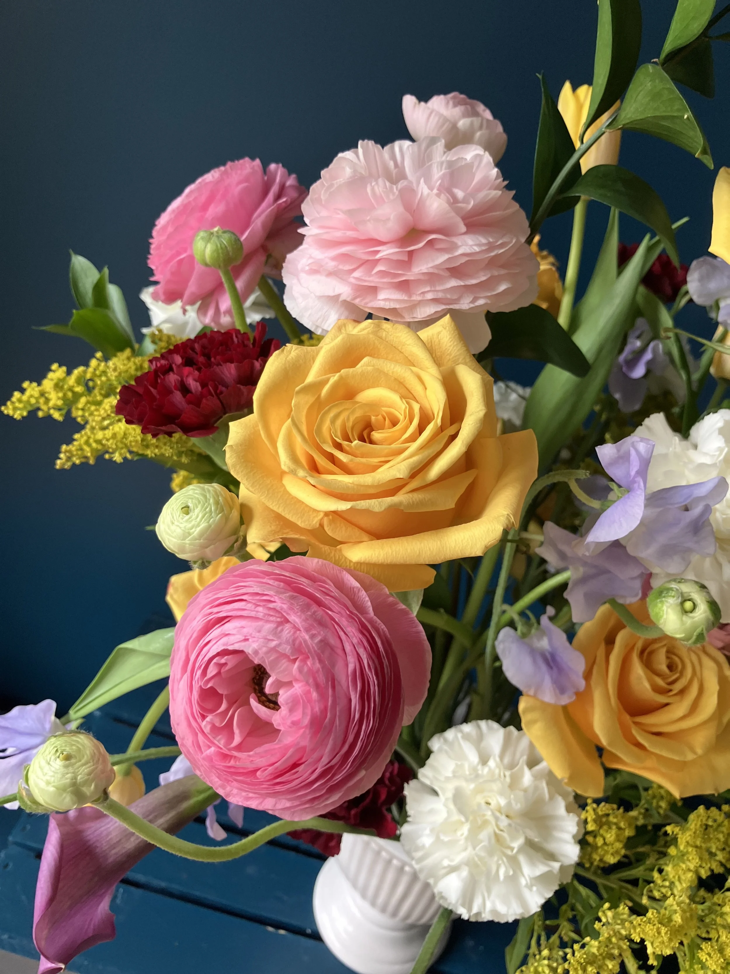 Mother's Day floral arrangement with yellow roses and spring blooms in a vase against a dark background