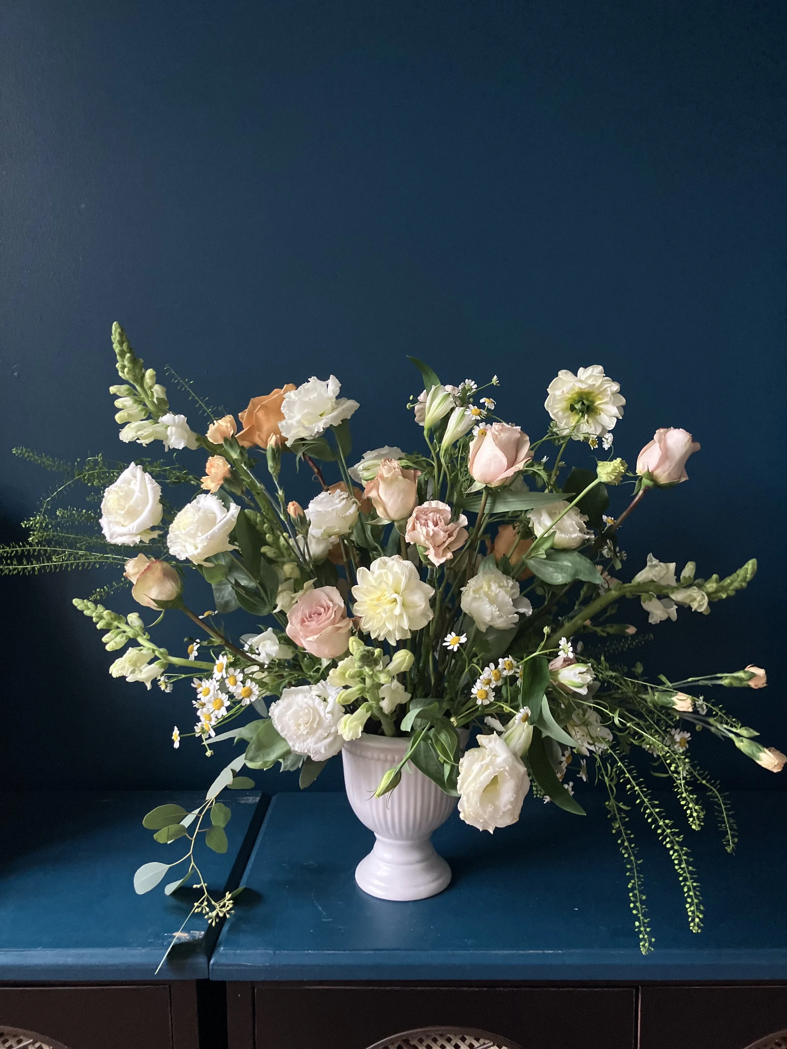 Made as a gift for sending condolences, this beautiful arrangement in white vase shows delicate lisianthus, copper and cream roses, white snapdragons and pink carnations.