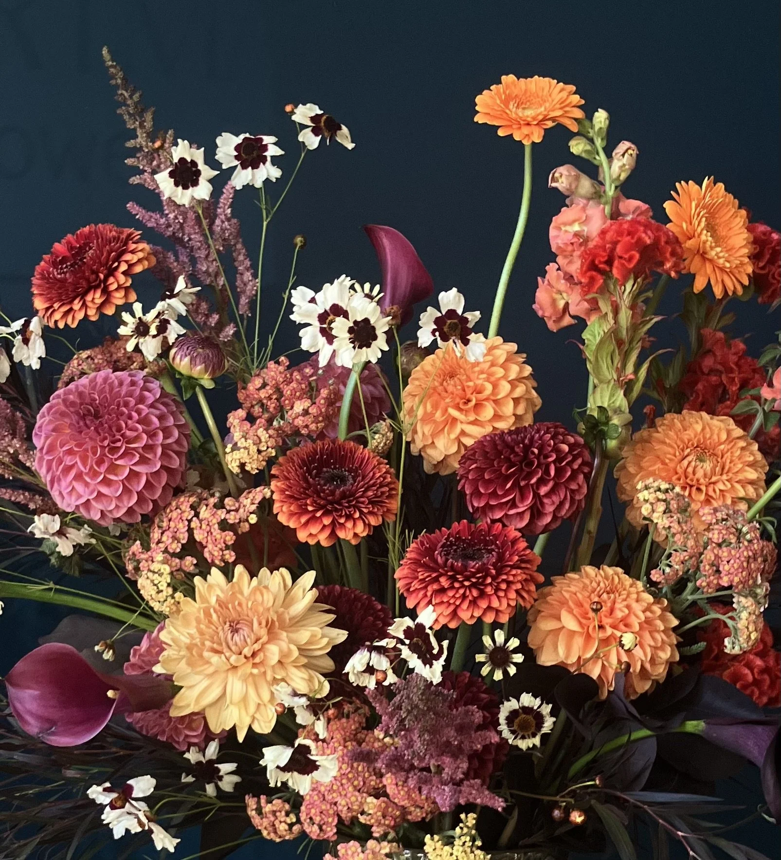 Orange and red flowers designed in vase by a Portland florist, Portmanteau Flower Co, for delivery to a business