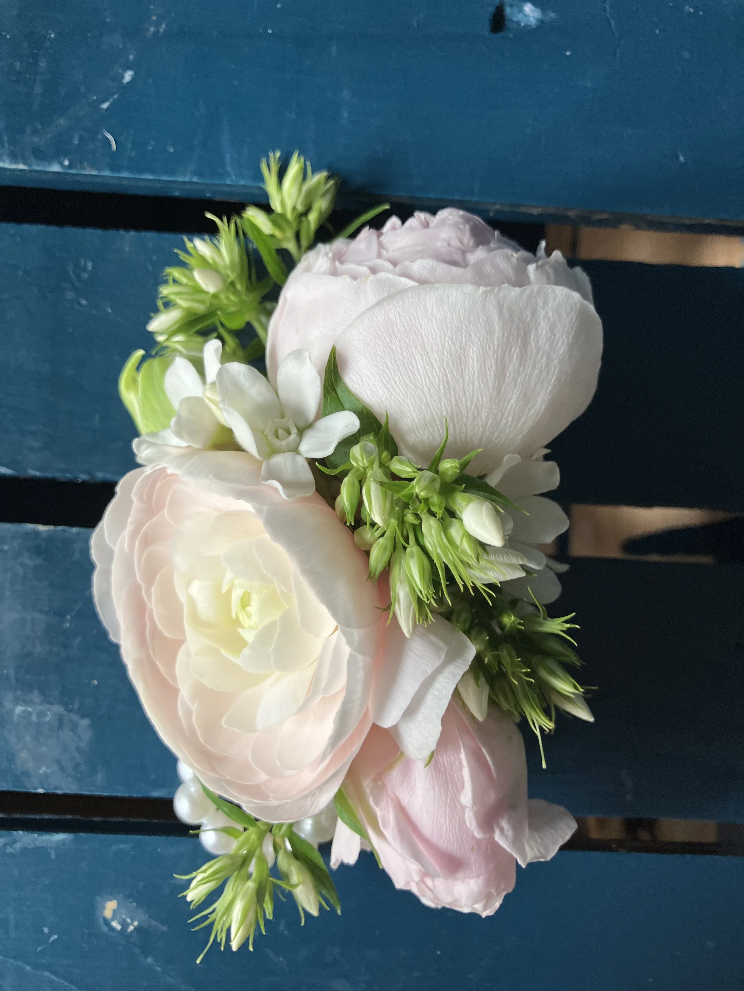 A high school prom corsage made of white peonies on a blue background