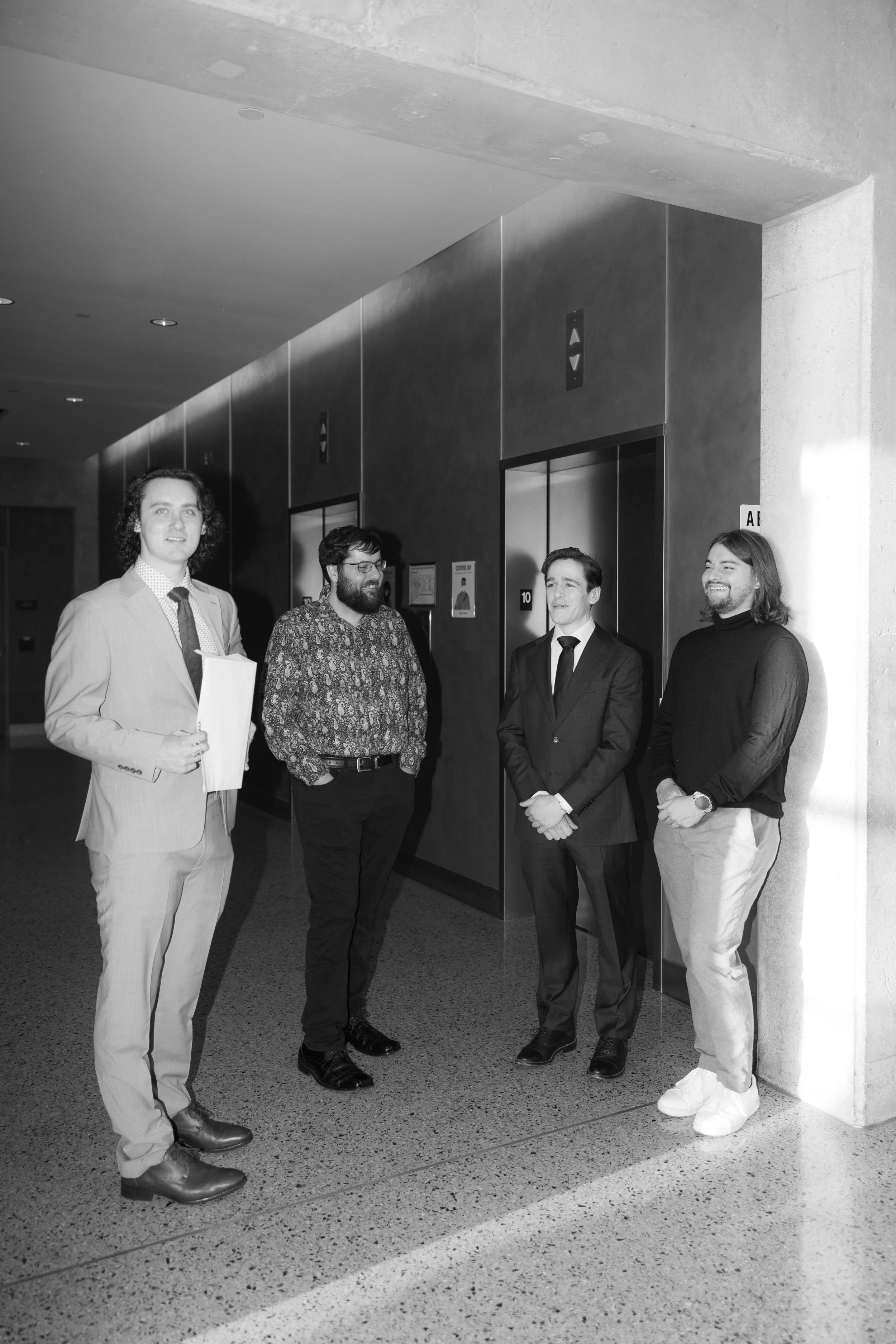Four men standing and talking near an elevator in a modern building