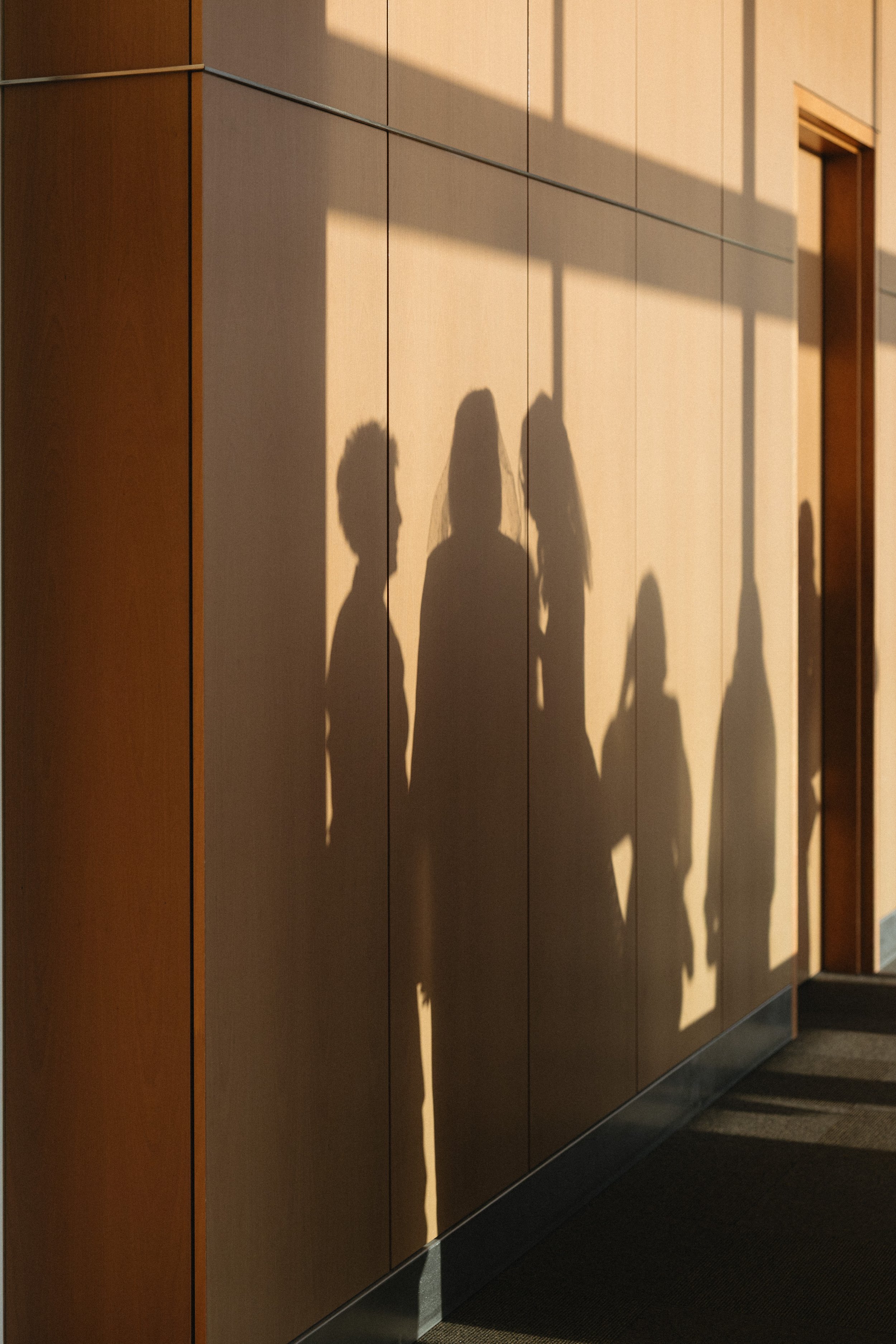 Shadows of a group of people on a beige wall.