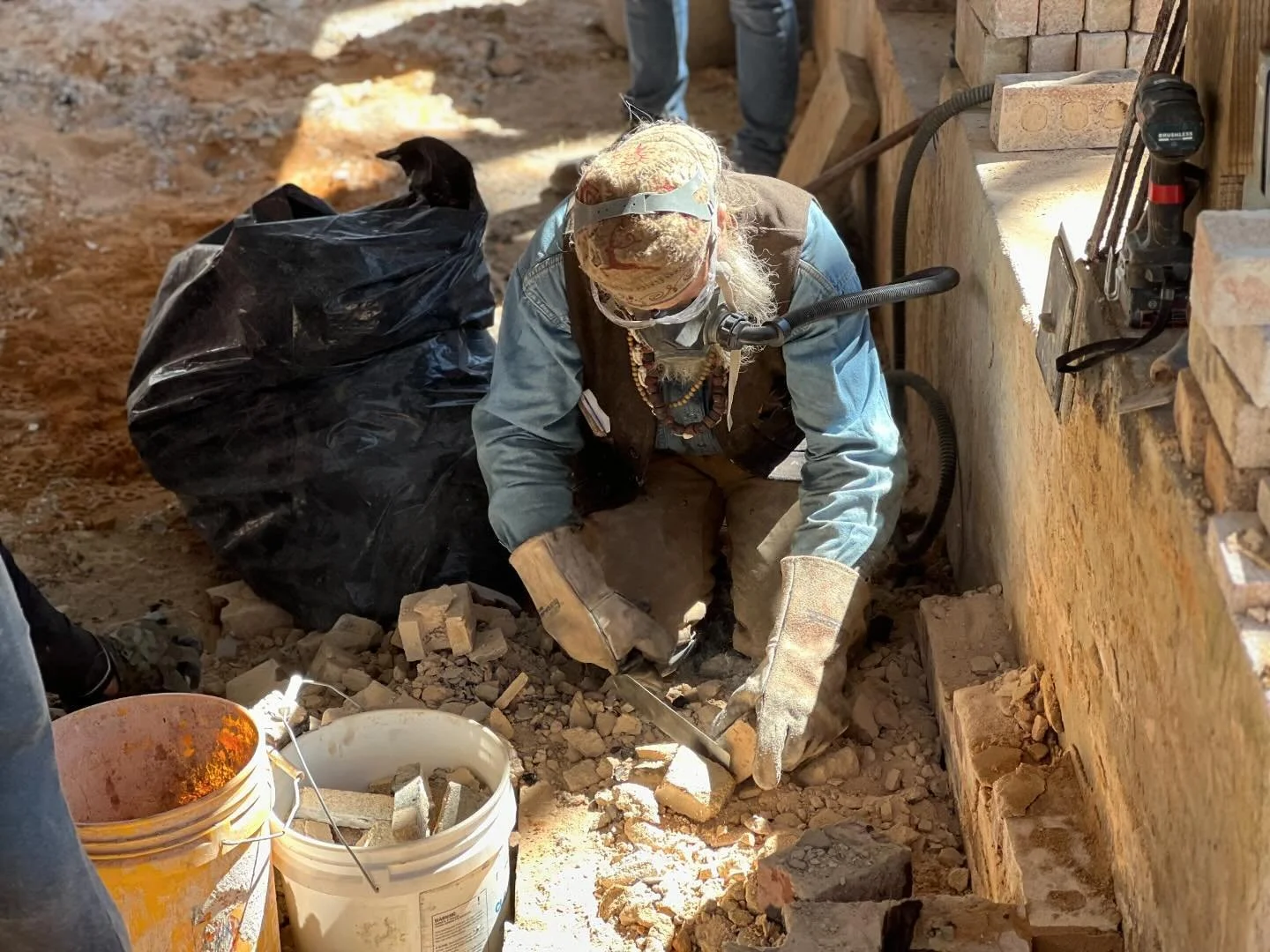 Man in face shield cutting brick